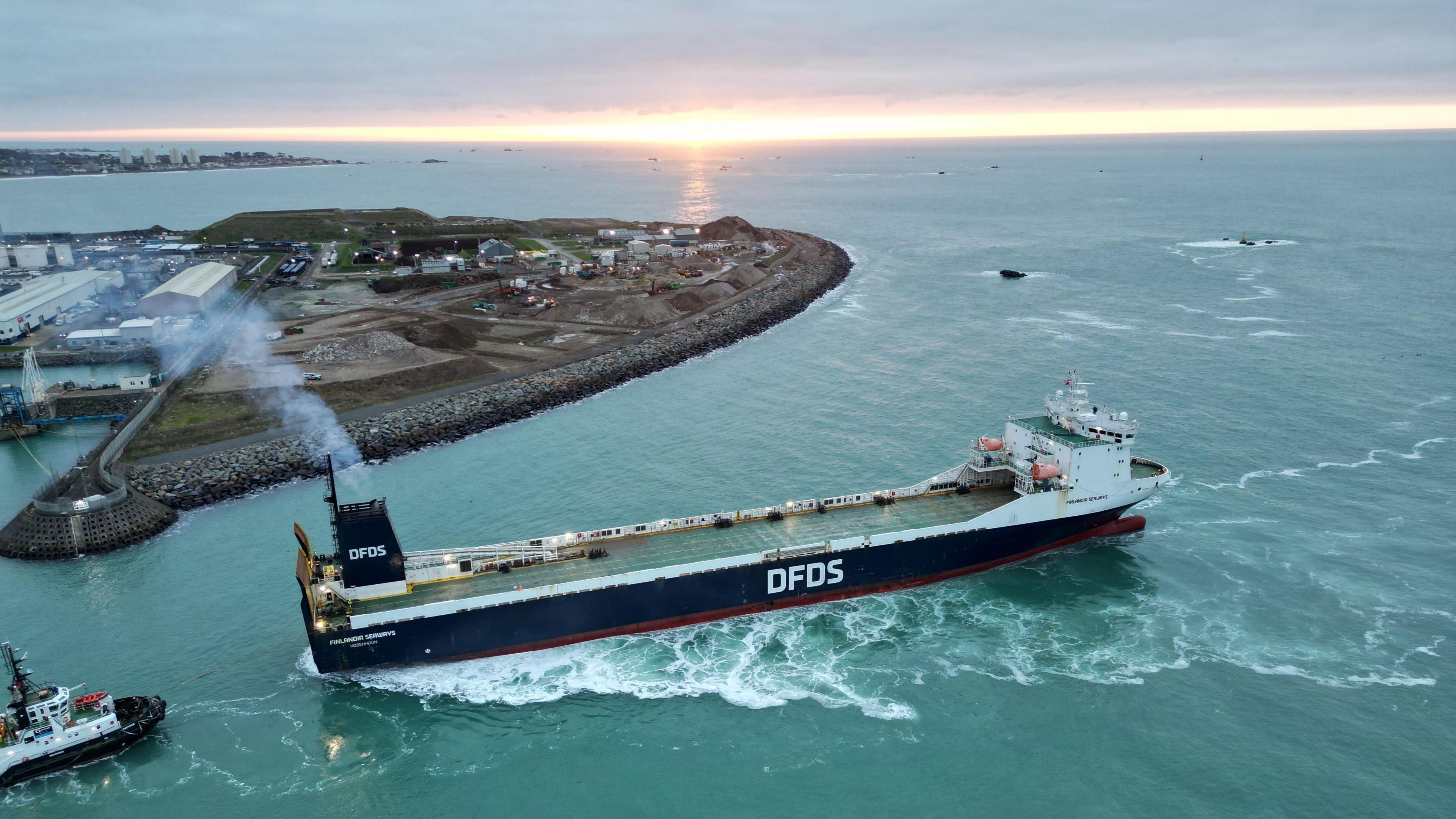 A large blue DFDS ferry pulls out of Jersey's harbour.