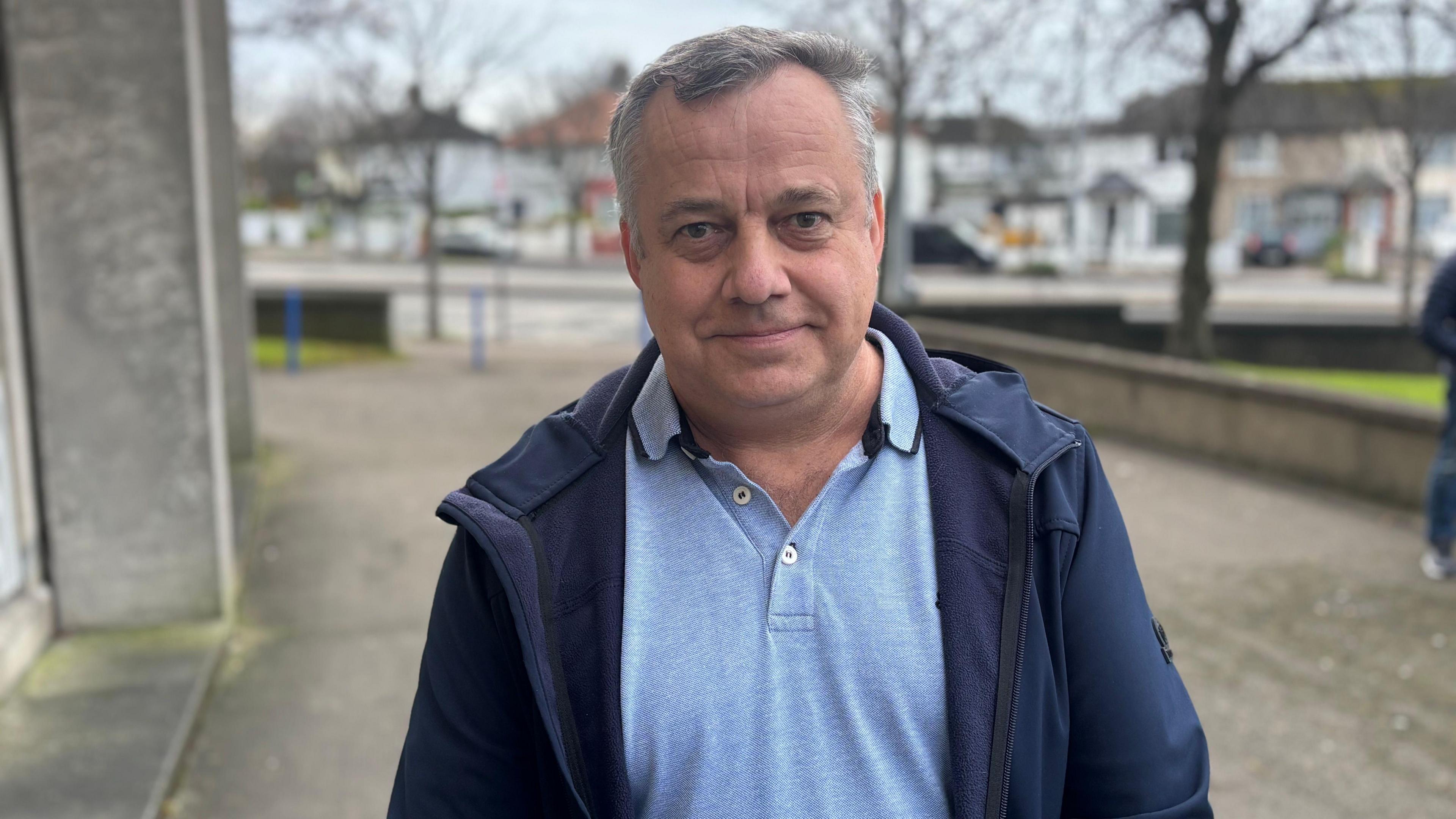 Ukrainian man wearing a blue jacket smiles at the camera 