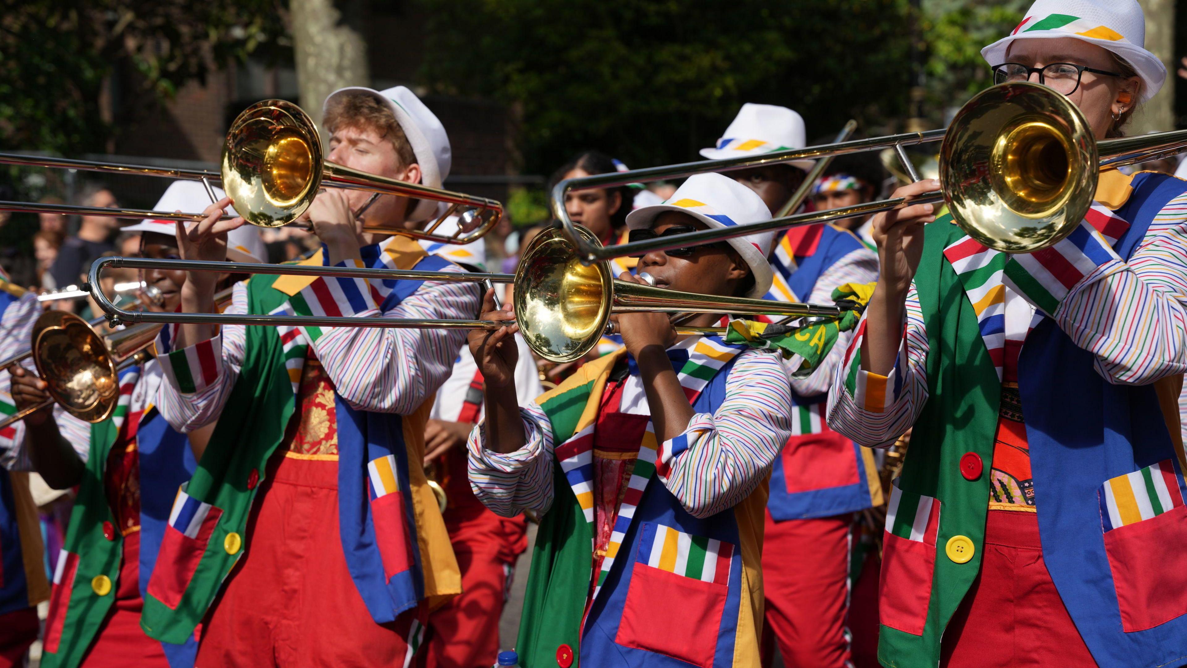 Trombone players in brightly coloured outfits