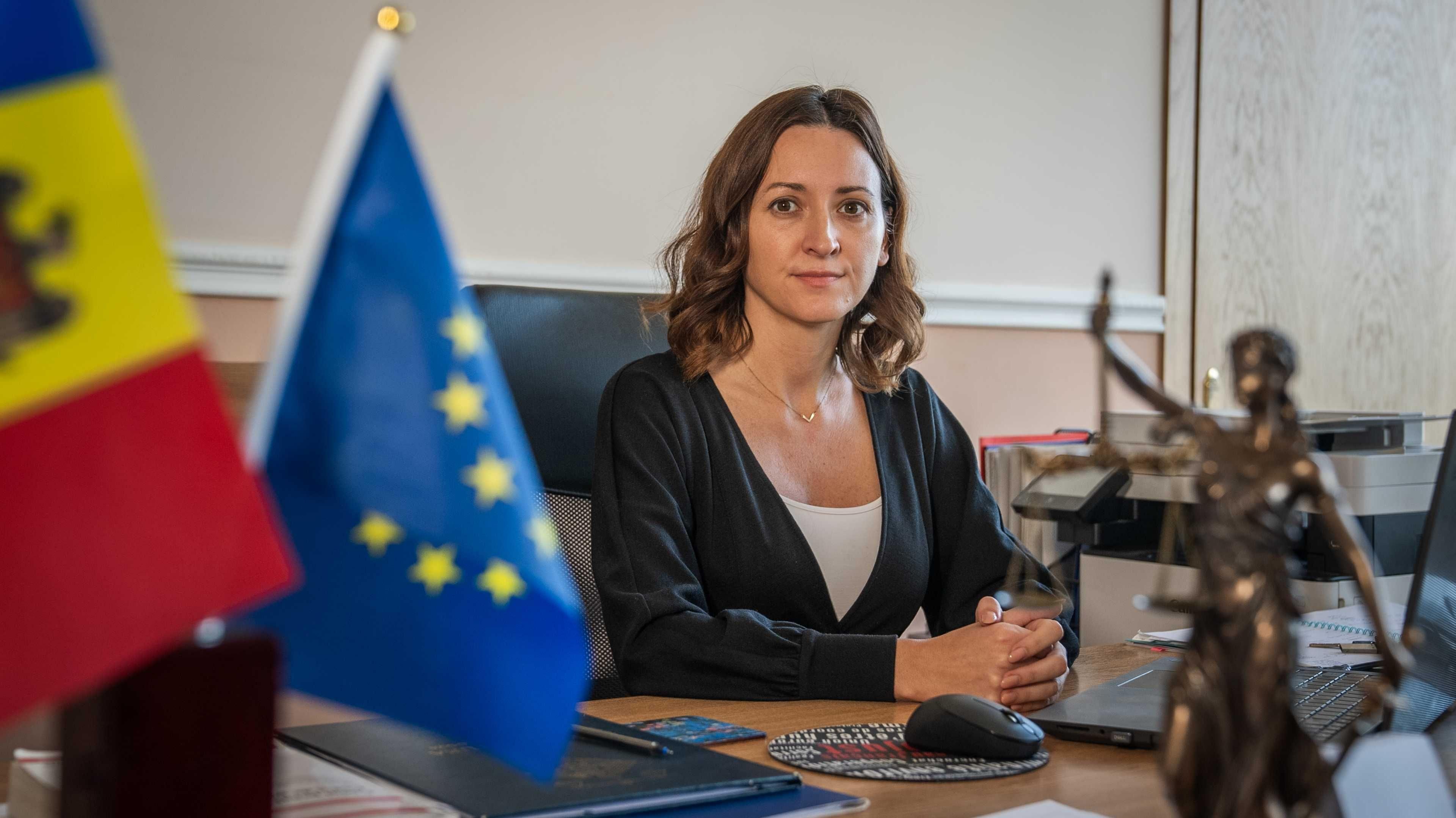 Moldova’s chief anti-corruption prosecutor Veronica Dragalin sat in her office at her desk. Visible in the image is a flag of Moldova and a flag of the EU.