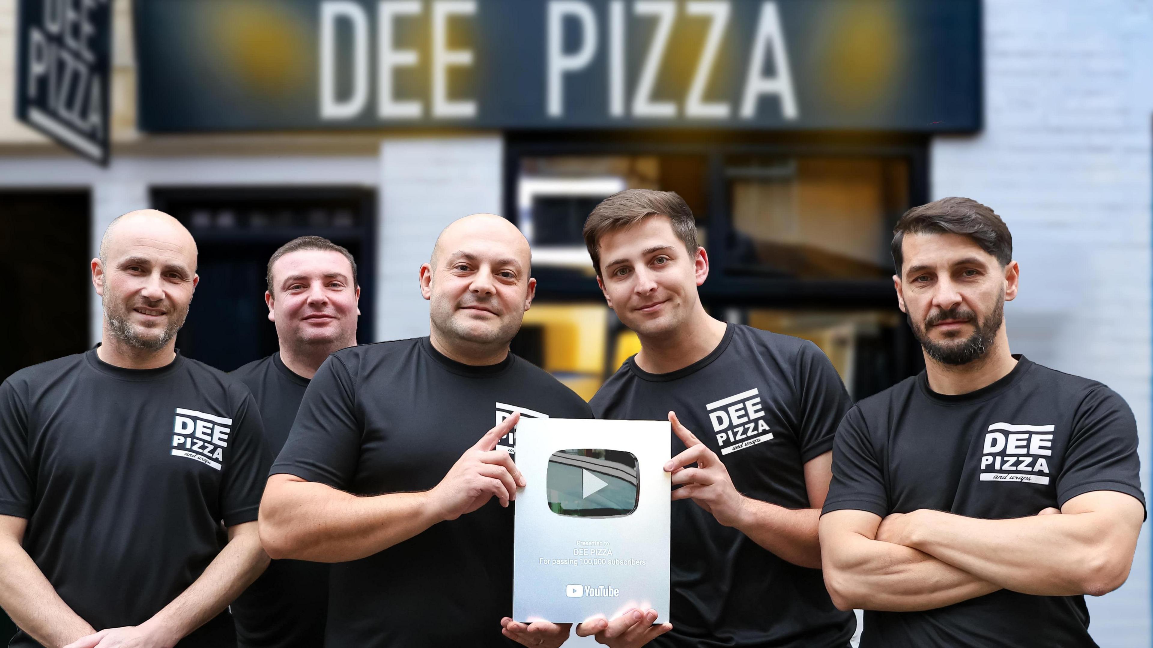 Angel Angolov smiles with his team outside Dee Pizza in Llangollen. They are holding a Youtube plaque given to creators that have more than 100 thousand subscribers on the platform.