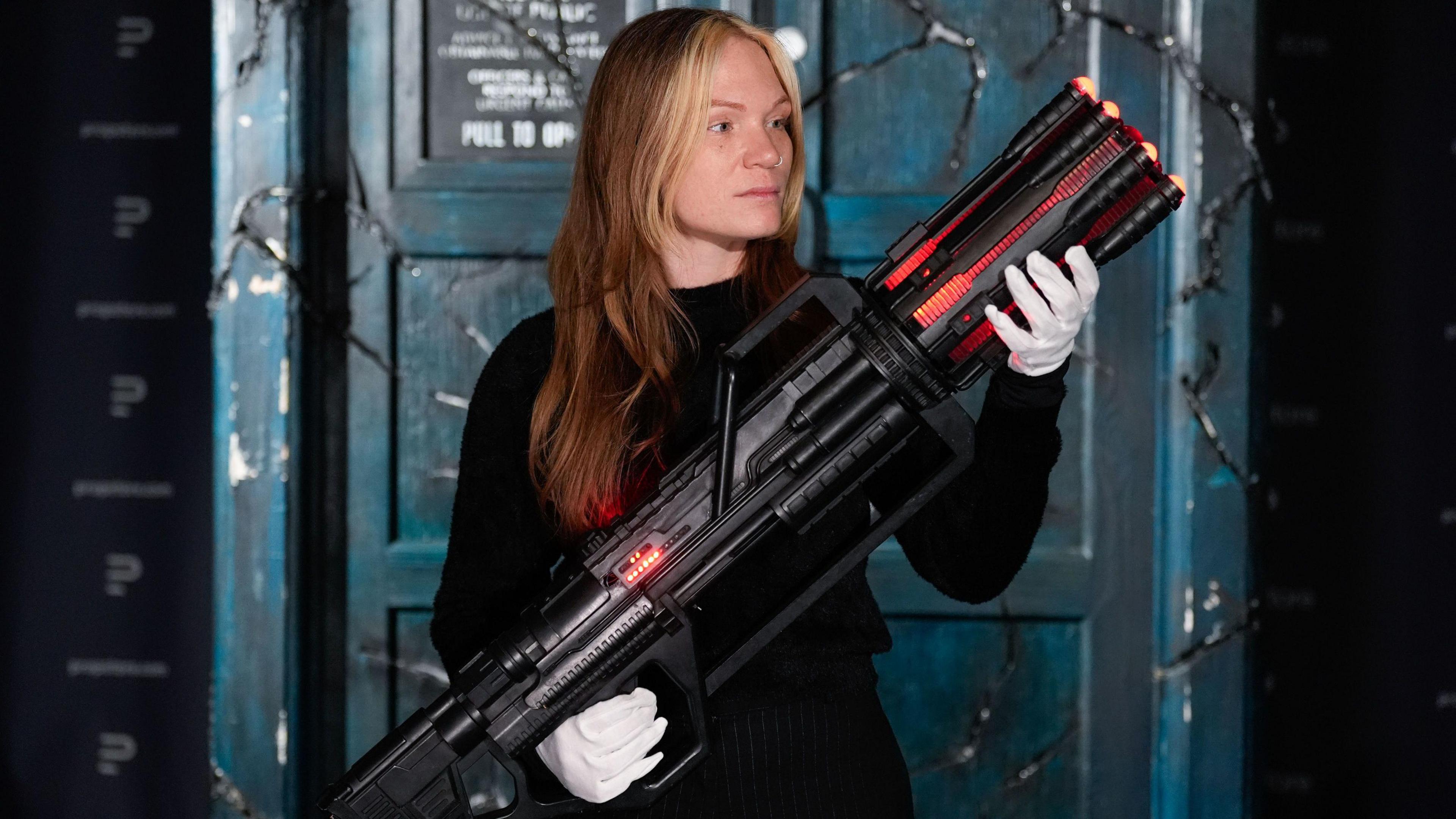 A Propstore employee holds Clara Oswald's (Jenna Coleman) Anti-Cyber gun from Doctor Who's series 7 episode 'Nightmare in Silver'.