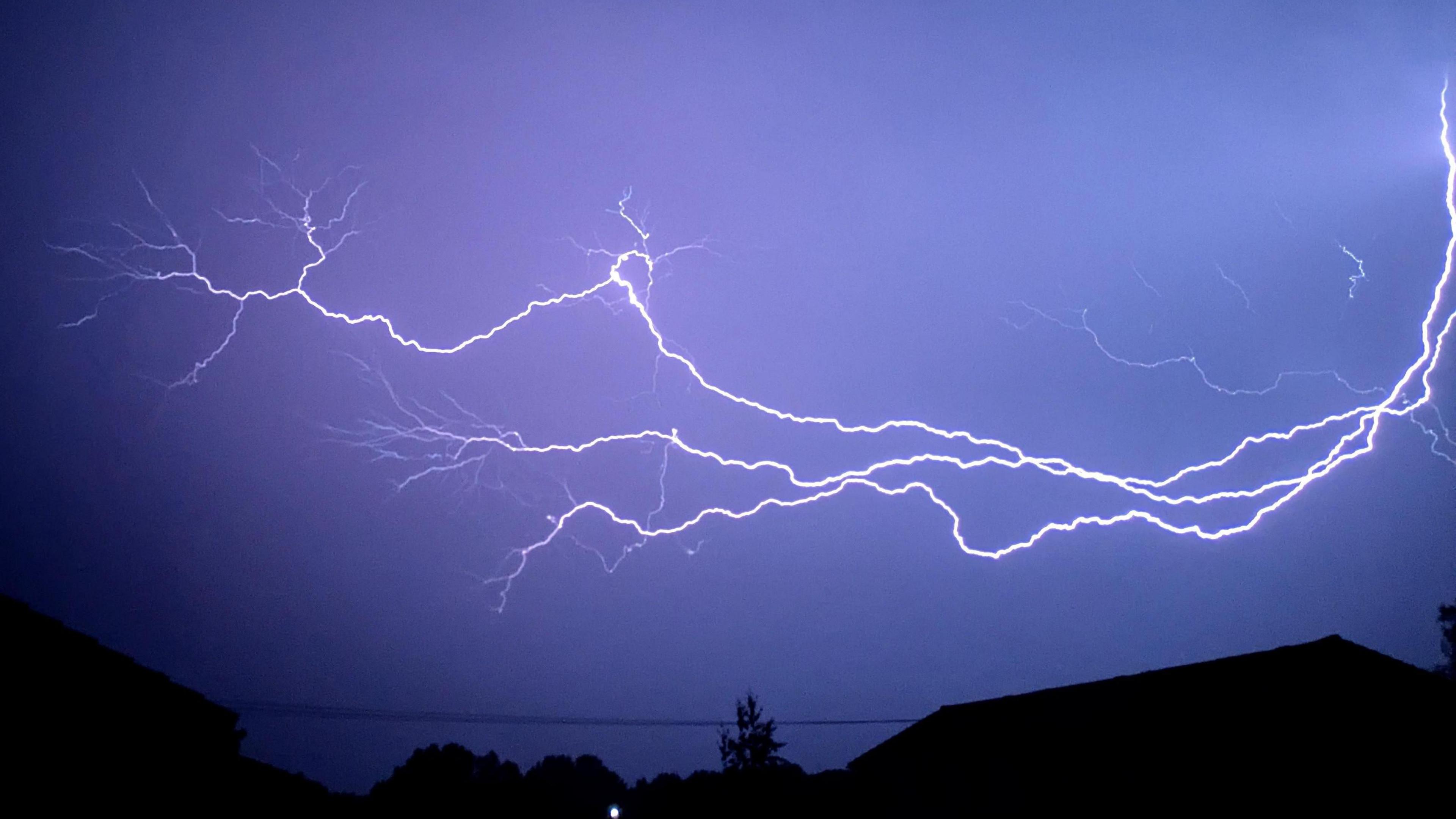 Flash of lightning in the night sky over a house