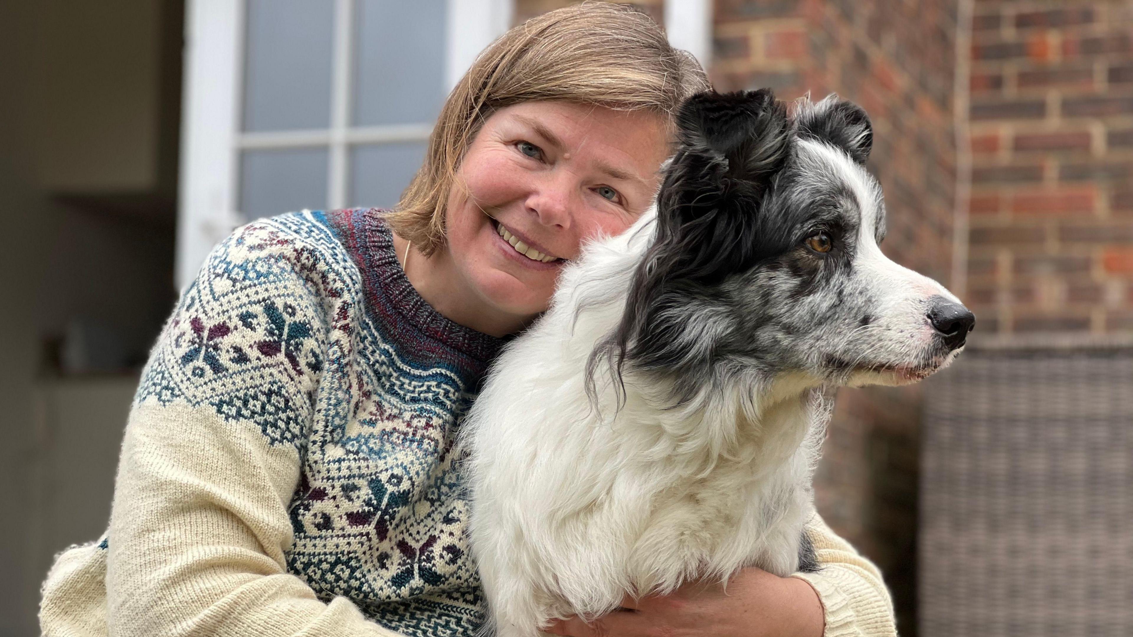 Harvey the border collie is being hugged by his owner Irene Hewlett outside their house in Reading. 
