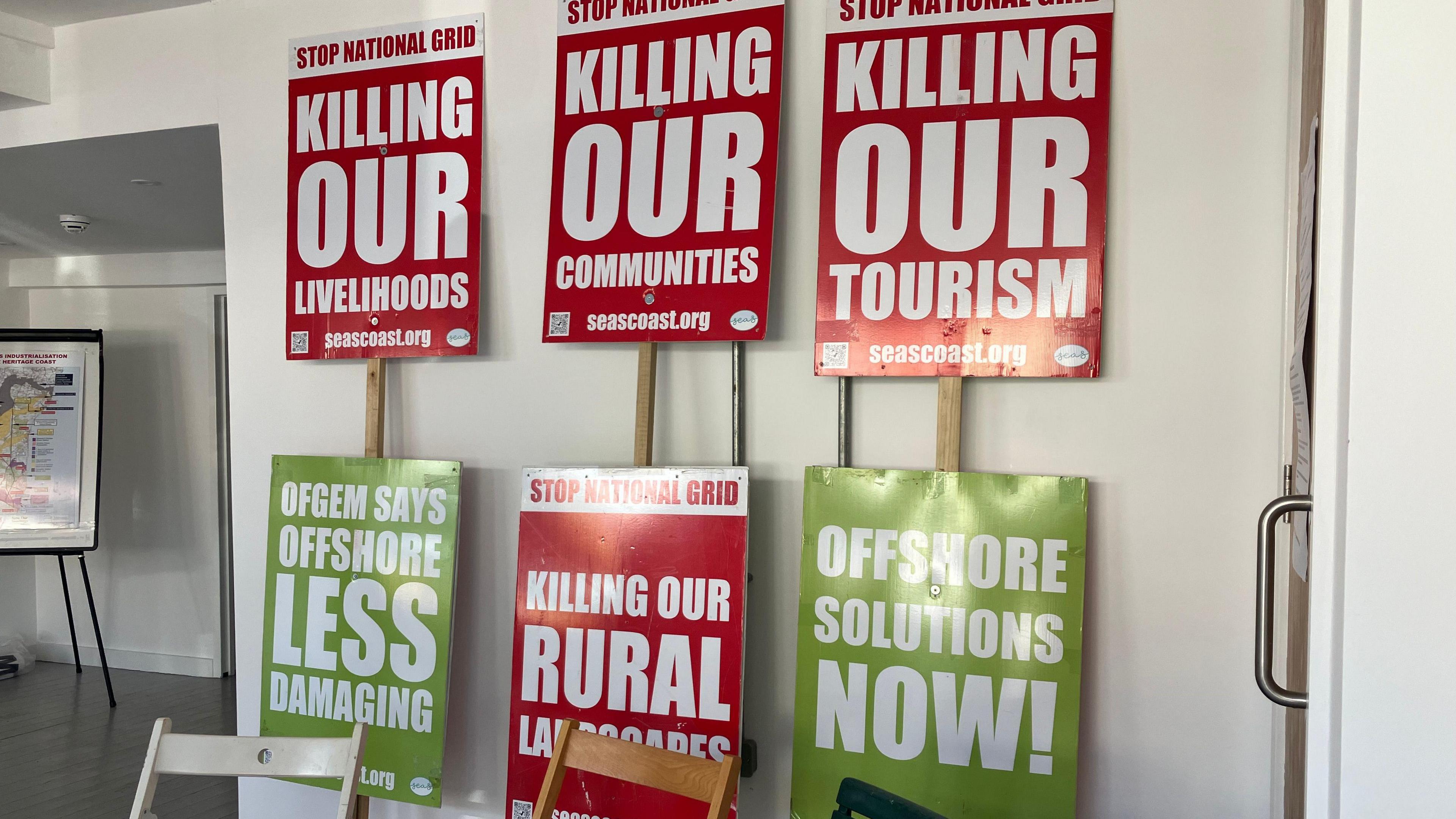 Red and green banners reading "Stop National Grid killing our livelihoods, communities and tourism" displayed against a white wall