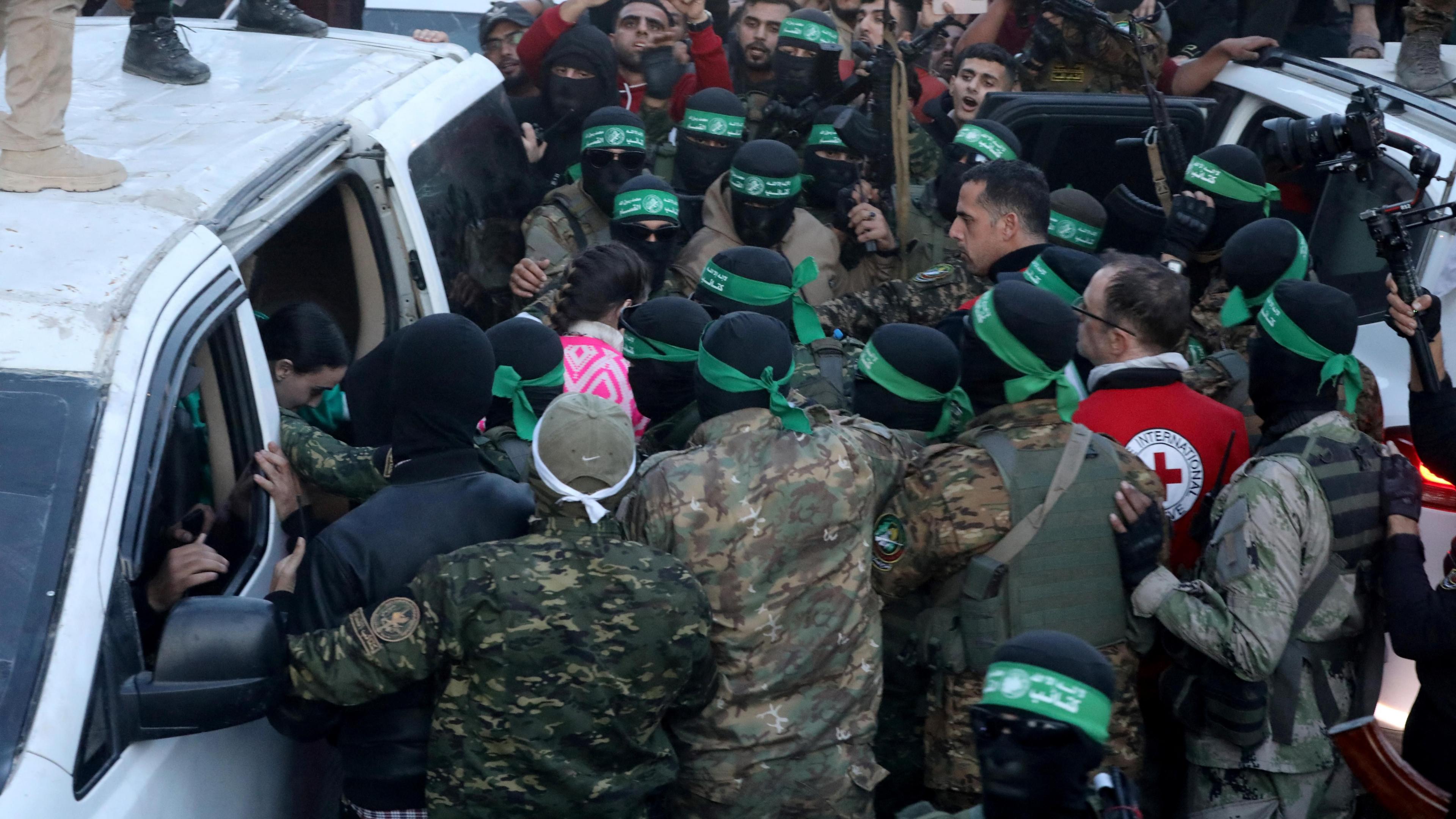 Hamas fighters escort three female Israeli hostages out of a van in Gaza City's Saraya Square before handing them over to Red Cross officials on the first day of a ceasefire deal, in northern Gaza (19 January 2025)