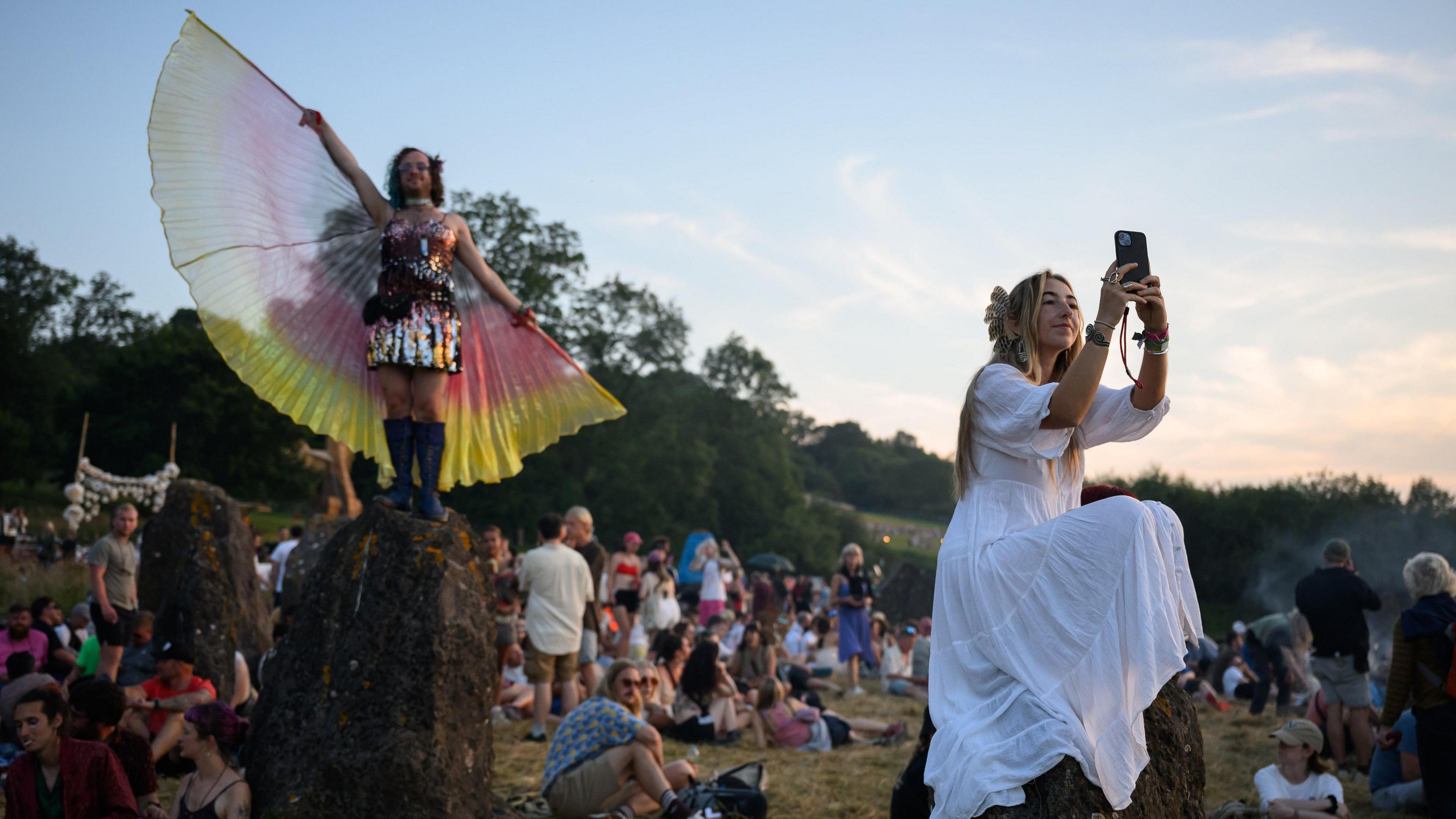 People gather at the stone circle at Glastonbury Festival at dusk