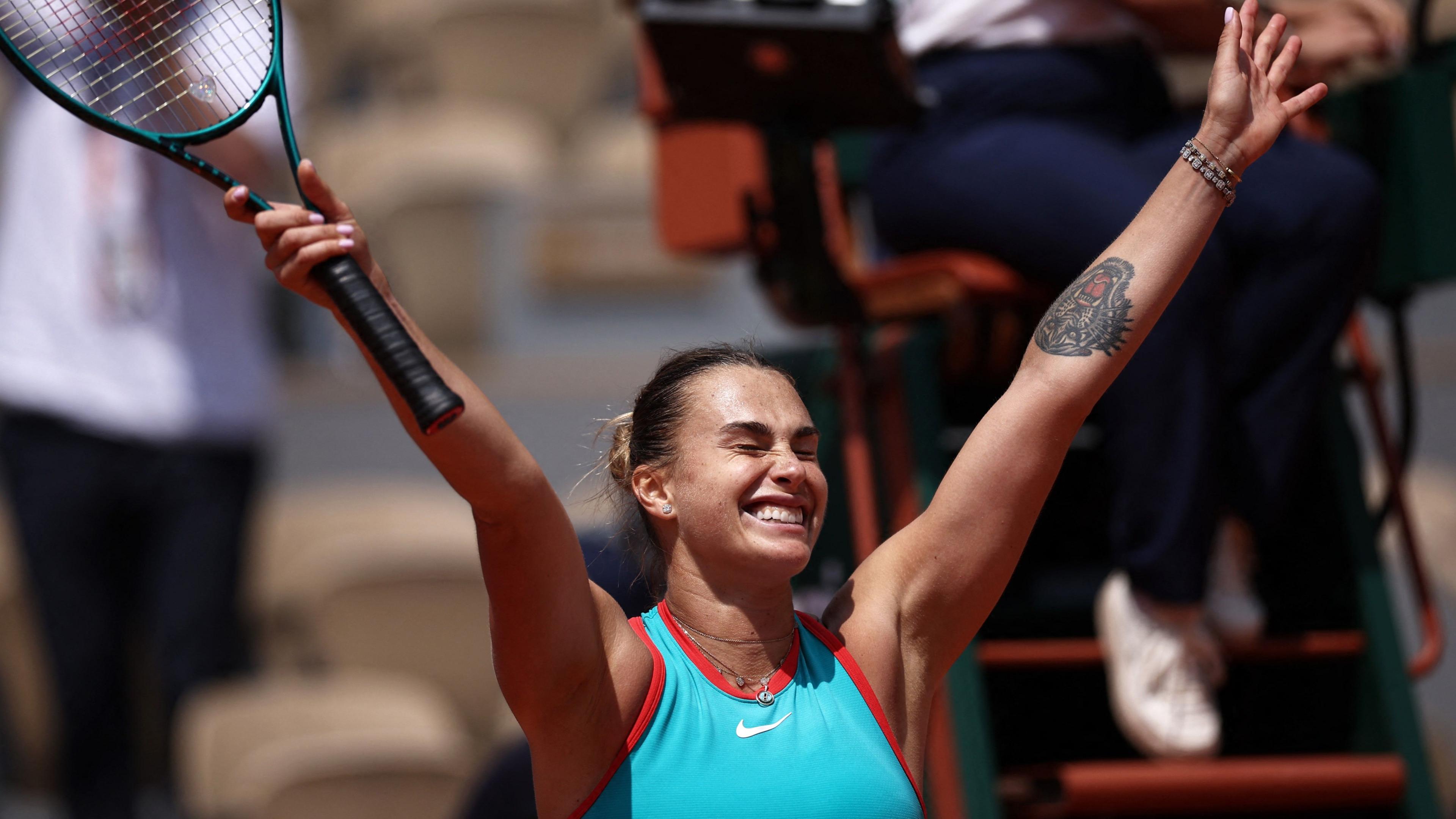 Aryna Sabalenka raises her arms in celebration after victory over Zheng Qinwen at the French Open