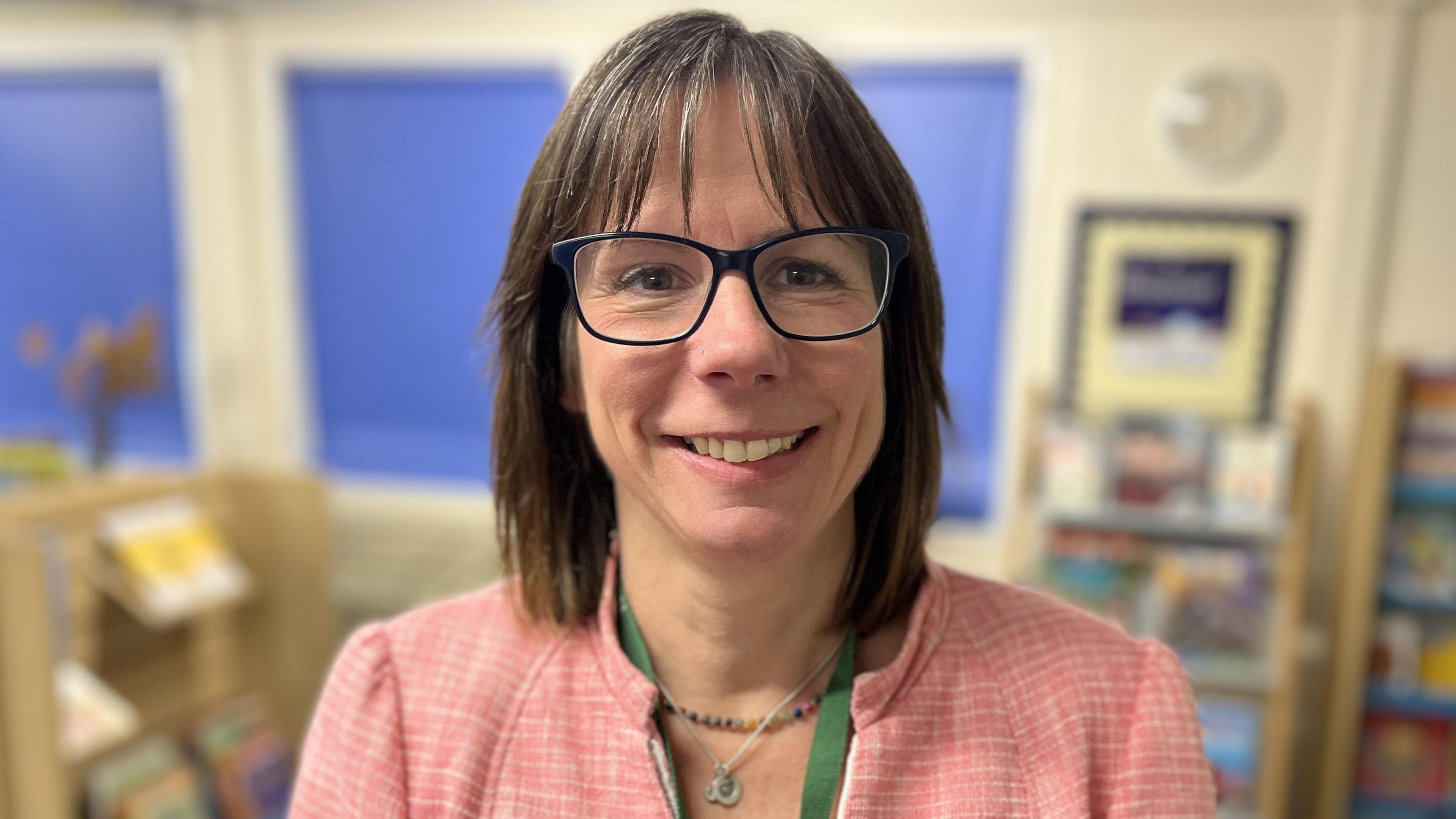 Candida Hutchinson, Headteacher at Gorse Hill Primary School smiling with bobbed brown hair and wearing black rectangular glasses