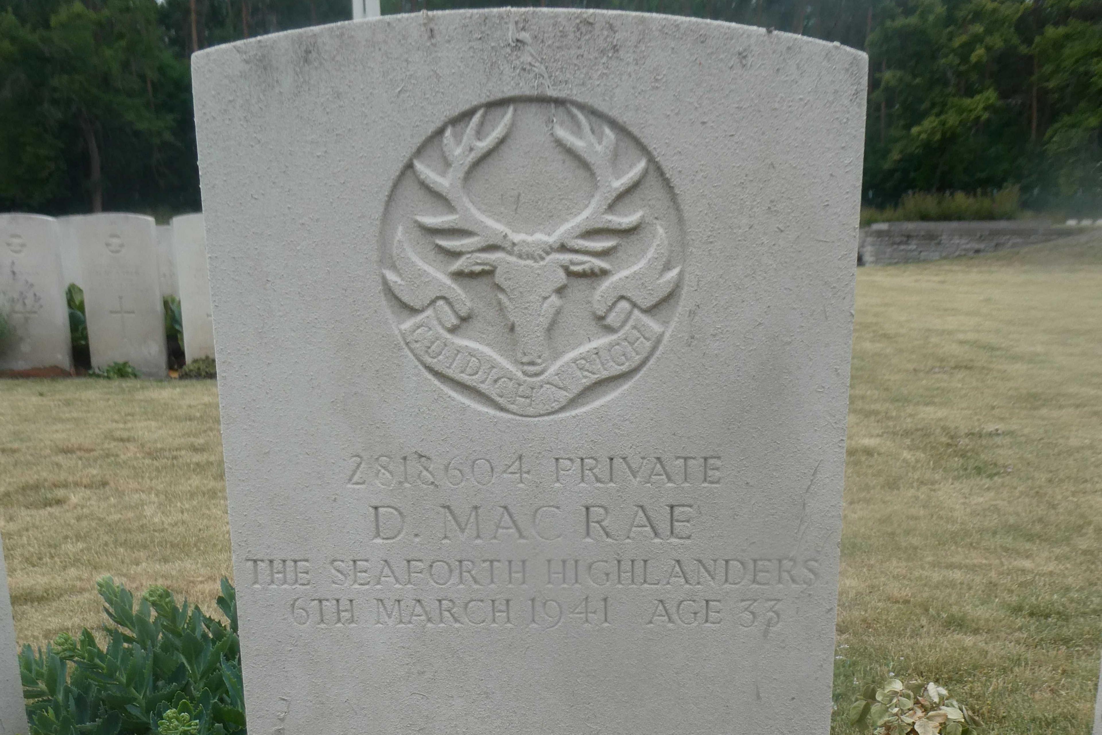 A single white headstone in the Commonwealth War Graves cemetery. It bears the name of D MacRae.