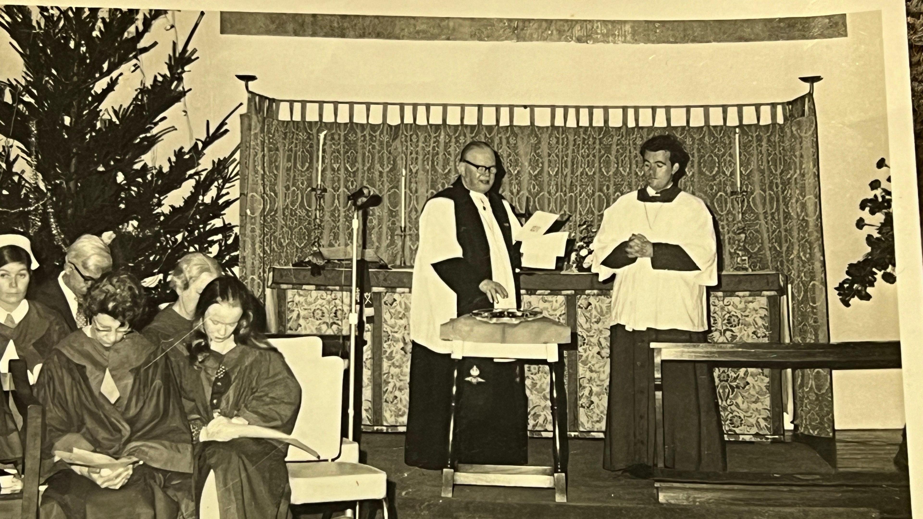 John stands next to a Reverend who is leading a church service in an old photo