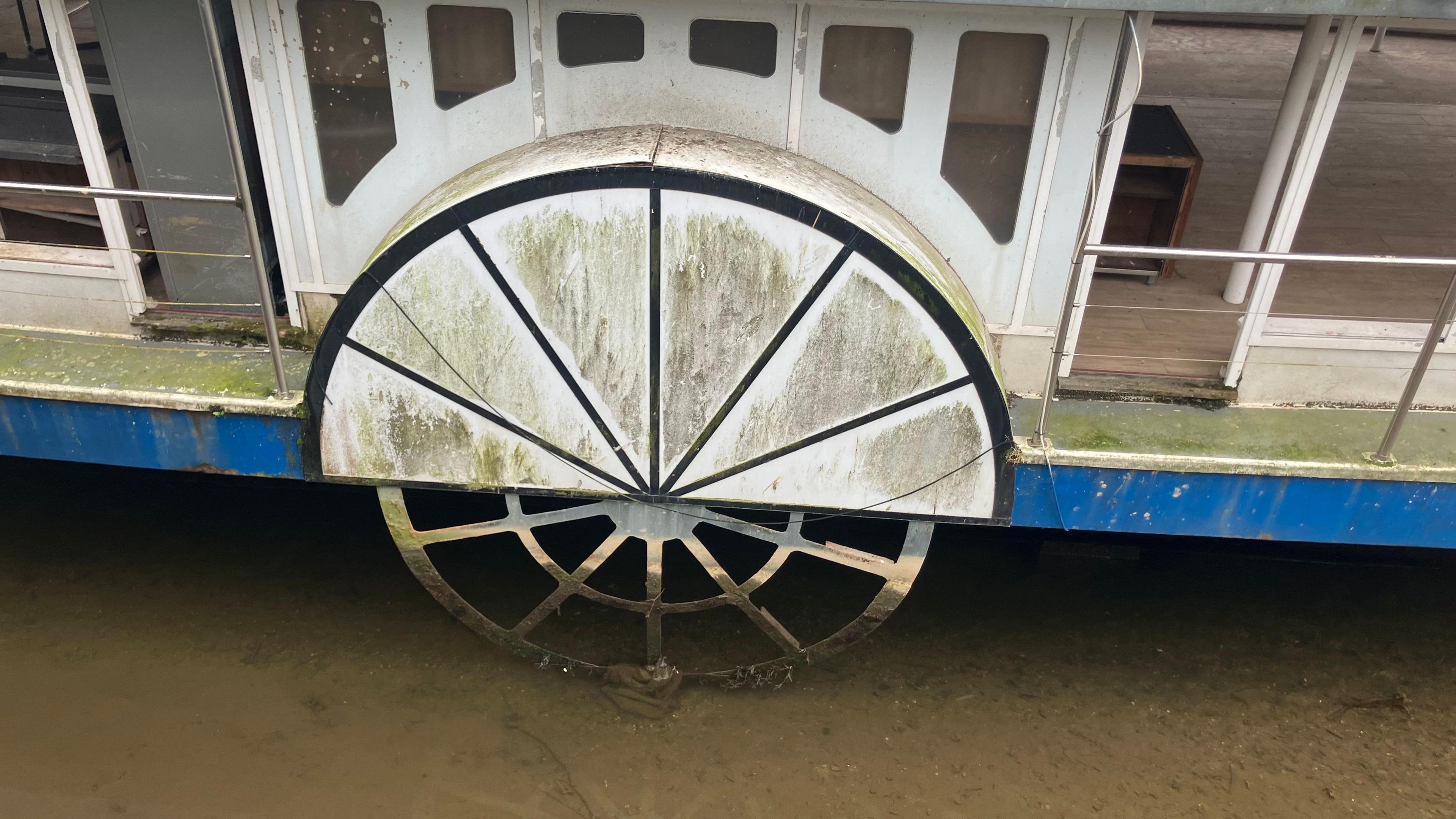 A paddle wheel on a boat. It is very dirty and covered in grime.