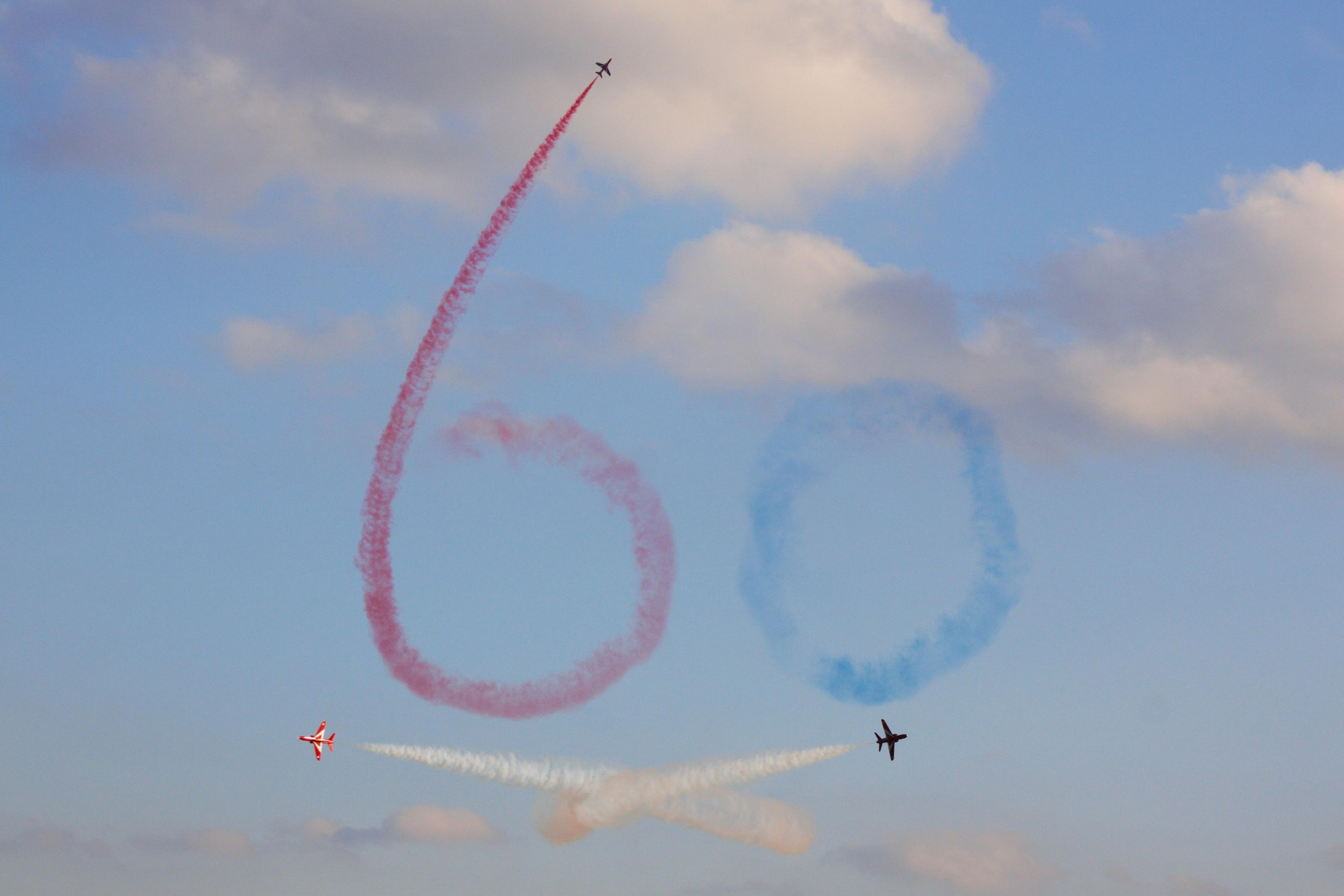 Planes write a red and blue '60' in the sky