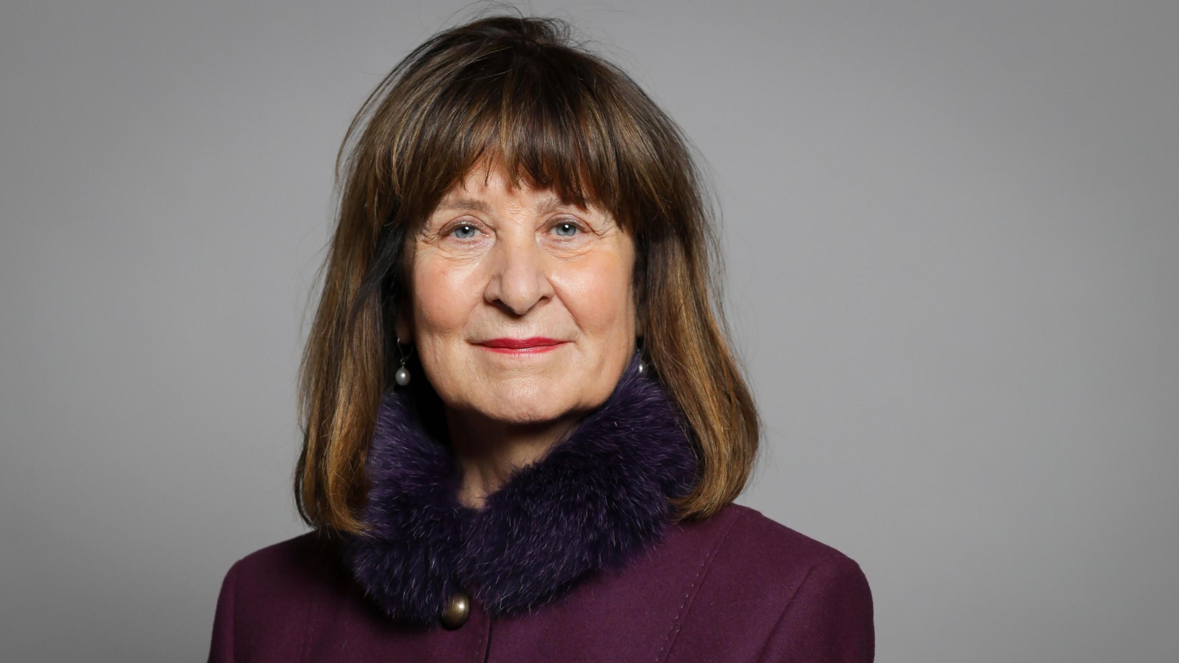 Baroness Helena Kennedy KC in a purple jacket with a fur collar against a neutral grey backdrop
