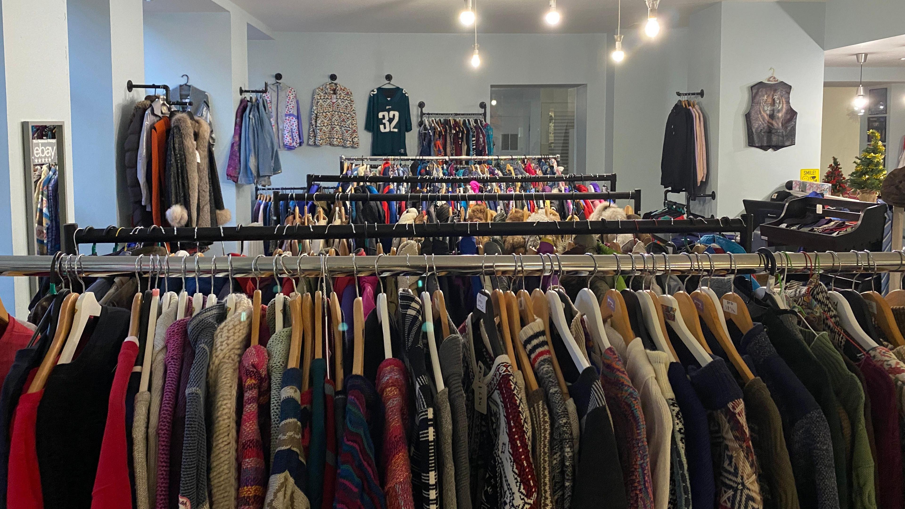 The shop is filled full of rails of clothes and coats of all colours. They are hanging from metal rails throughout the shop