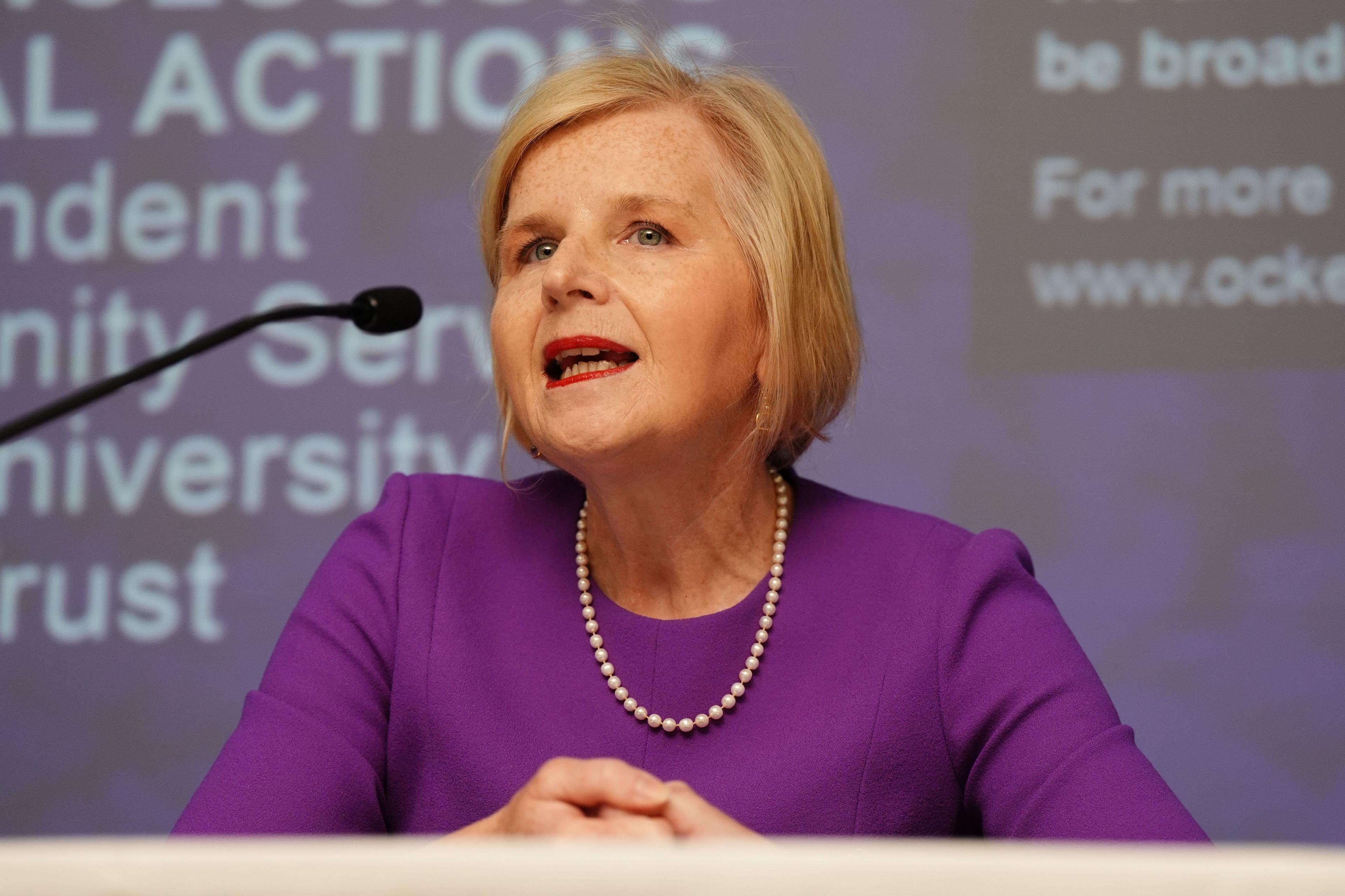 Donna Ockenden, who has abbreviated  blonde hair, speaks into a microphone. Donna is wearing a purple formal  and a achromatic  pearl necklace. A presumption    tin  beryllium  seen connected  the surface  down  her.