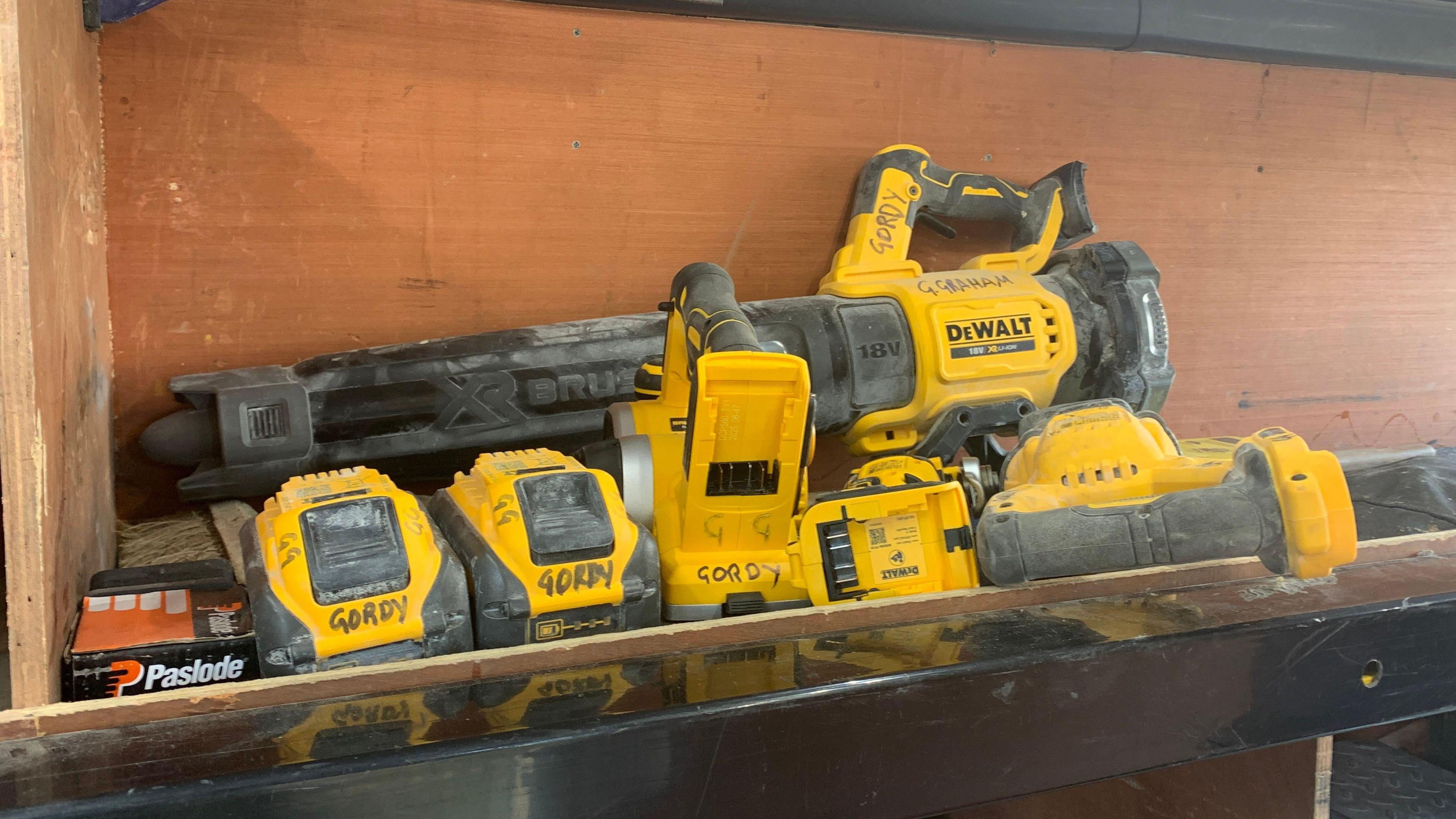A shelf full of black and yellow DeWalt-branded power tools are sitting on a shelf inside a van