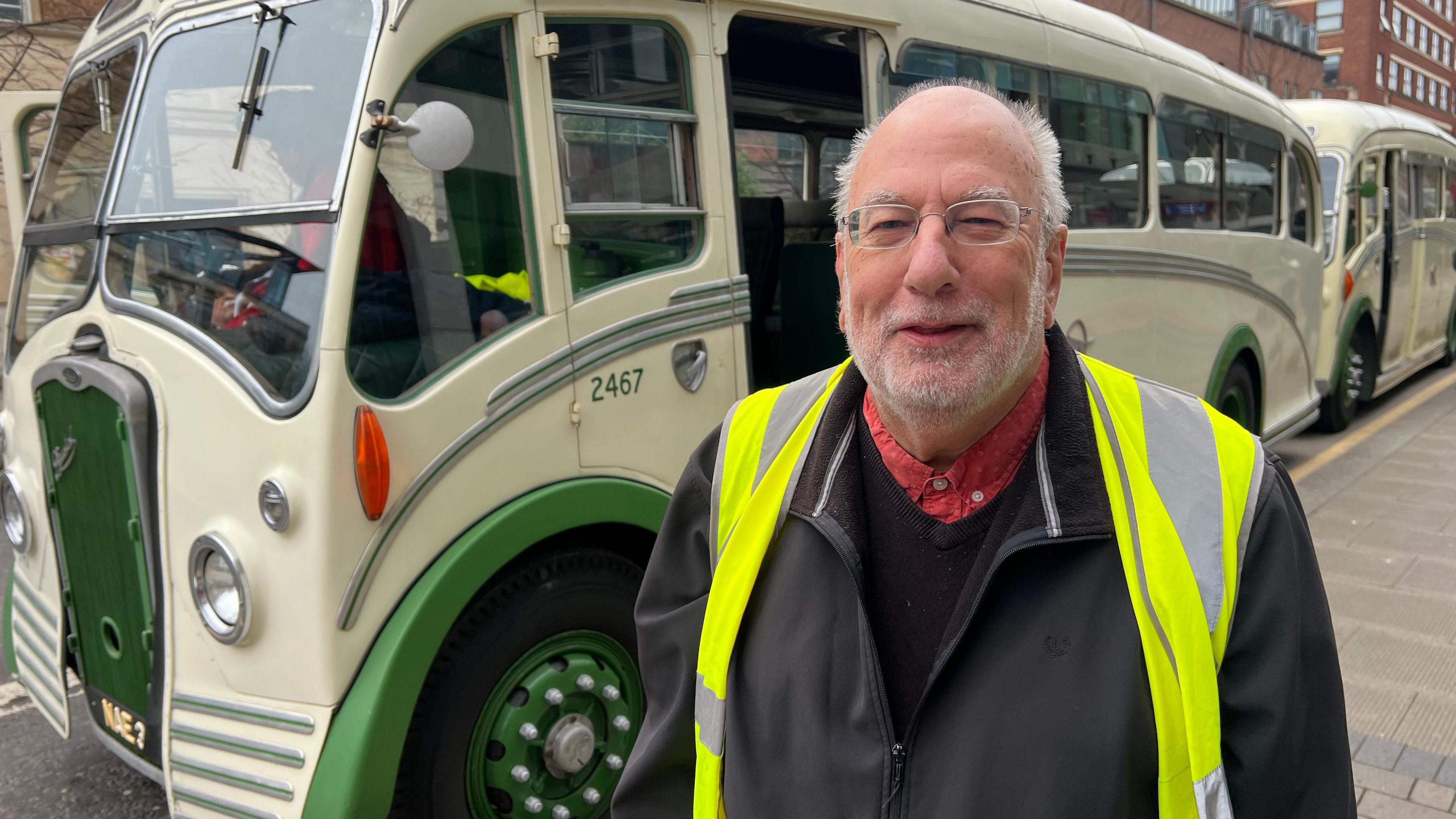 Martin Curtis smiling at the camera. He has a bald head with grey hair at the sides and is wearing spectacles. He is wearing a black jacket with a hi-vis vest.