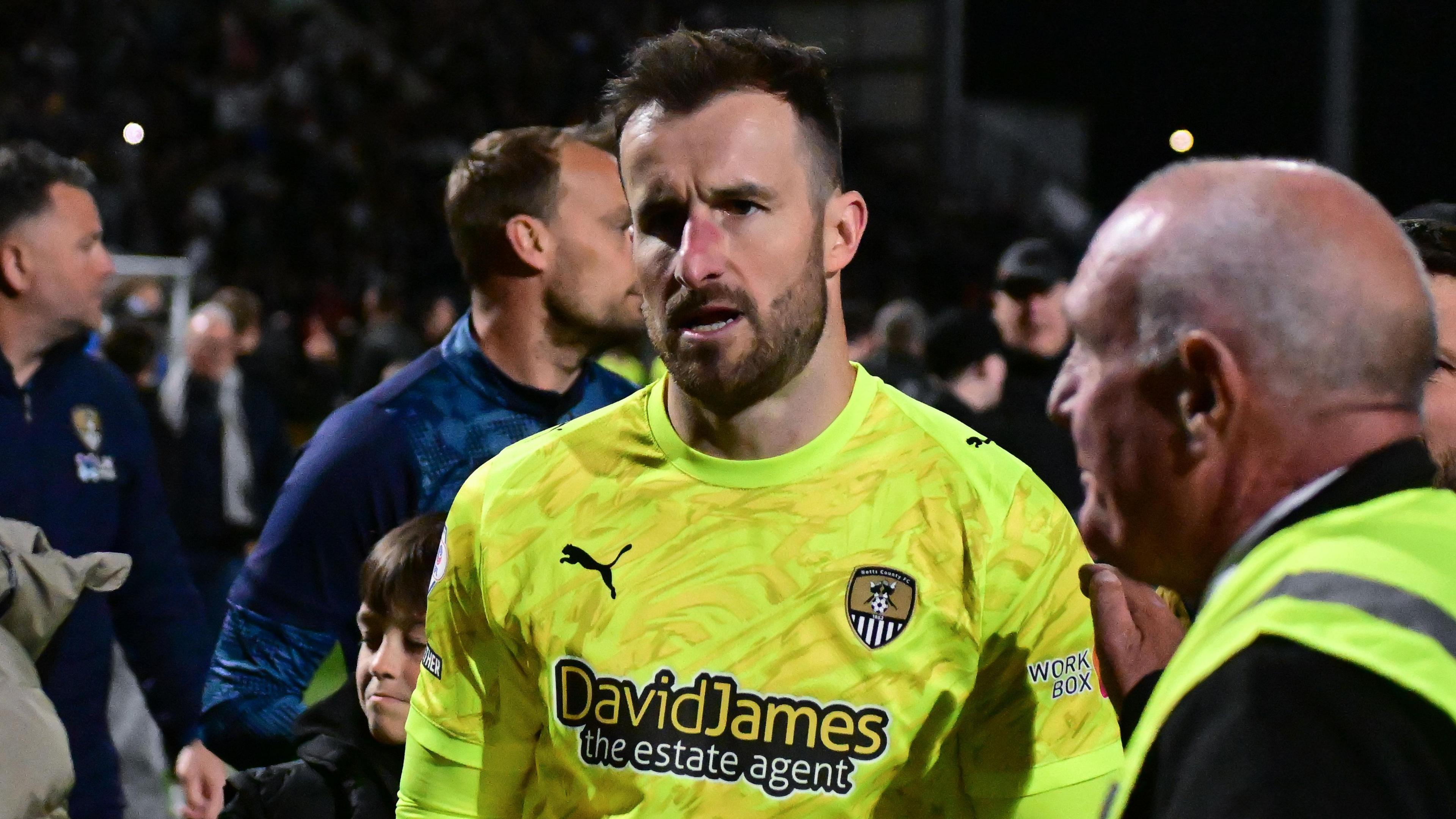 Notts County goalkeeper James Belshaw leaves the pitch at Meadow Lane while surrounded by fans and security staff after helping the Magpies reach the League Two play-off final
