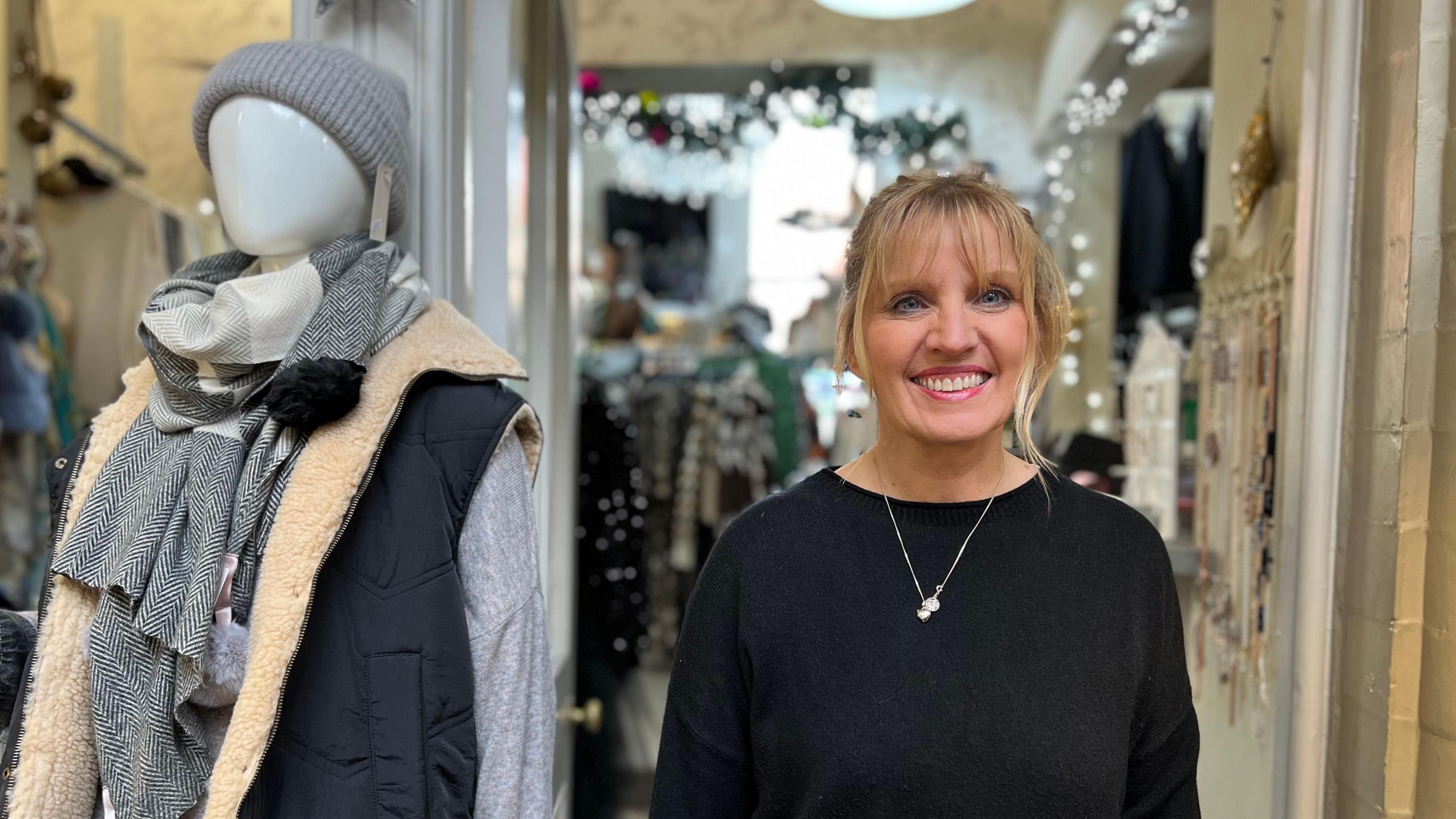 Deborah Bellamy owner of 'Hidden Wardrobe' in Corn Exchange in Leeds. She is standing in her shop front with clothes in the background. 