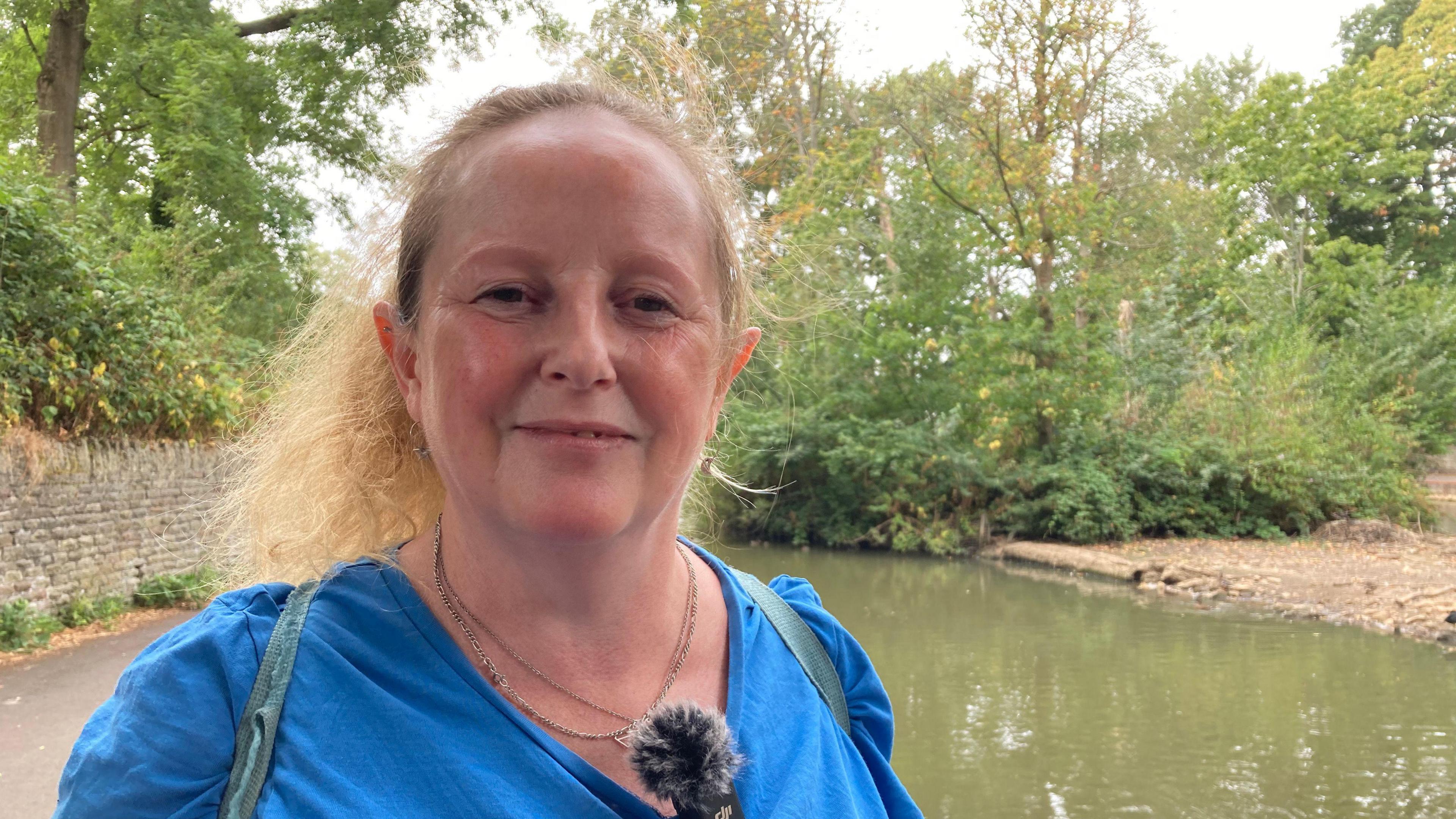 Ceri Dunning stands in front of the pond in St George Park in Bristol, a small island is visible behind her.
