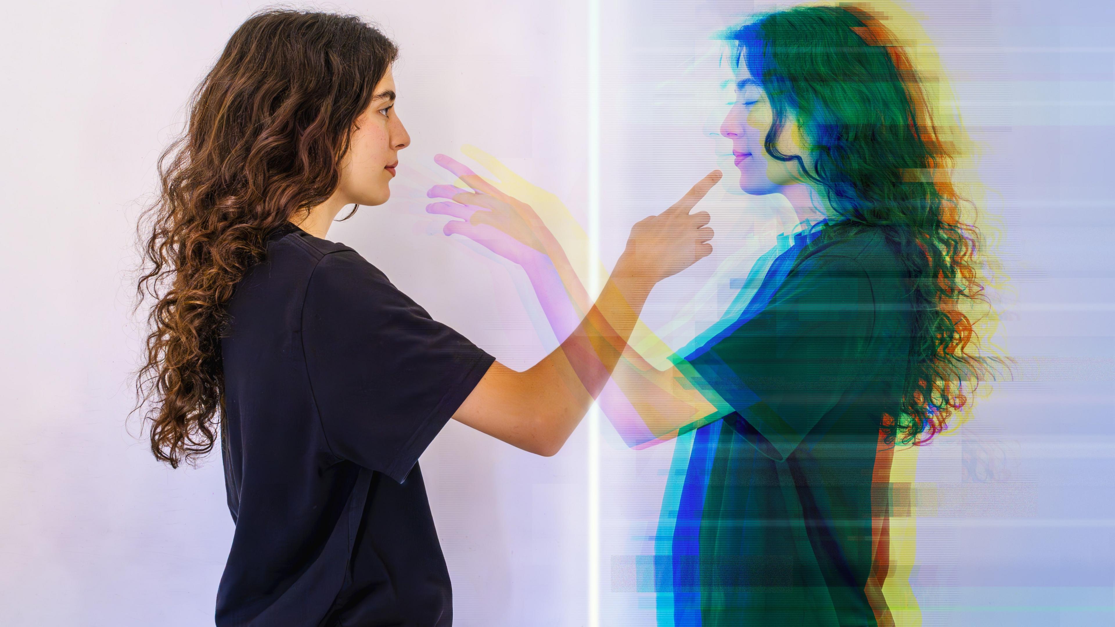 A lady points to a reflection of herself