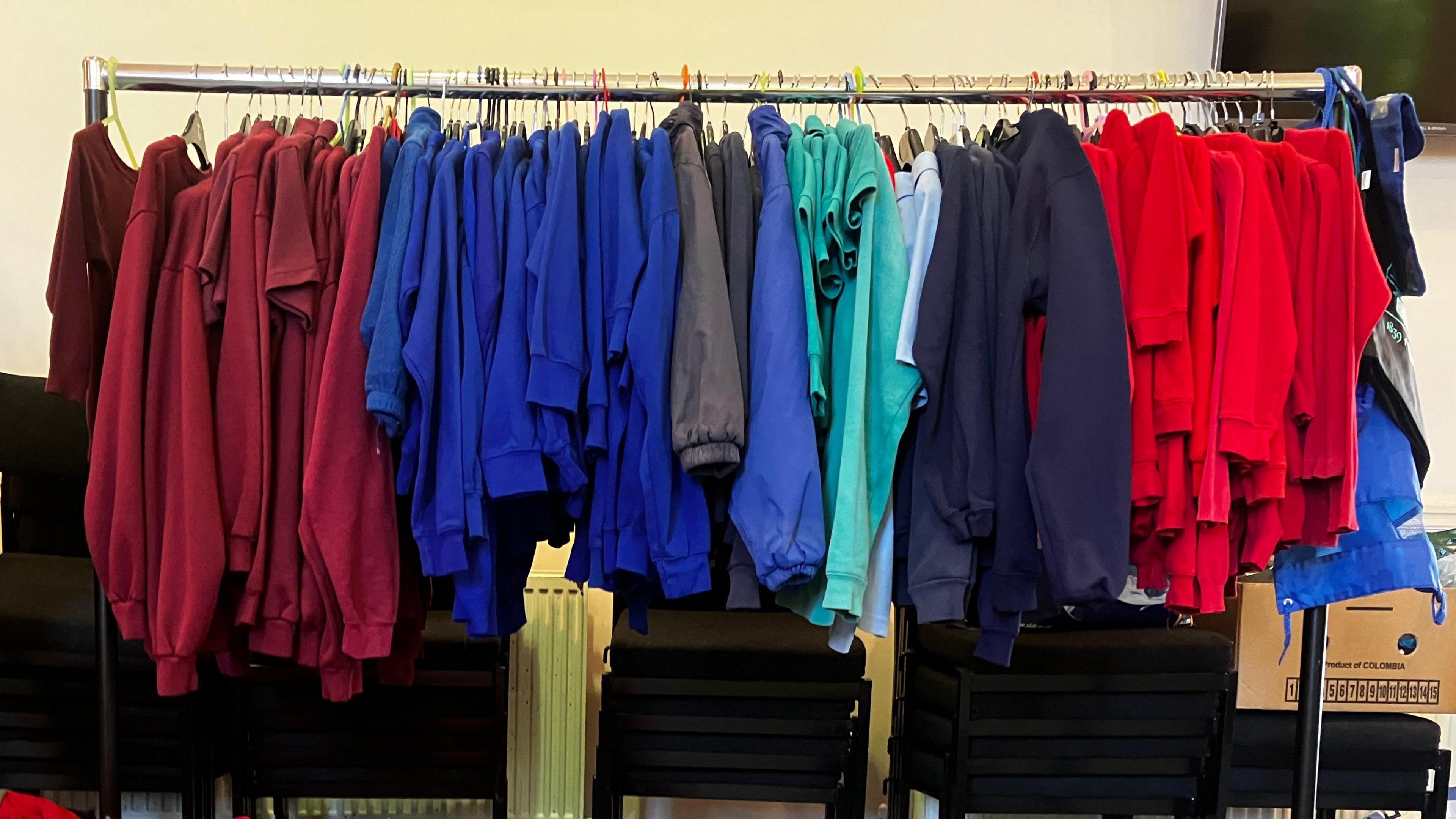 School uniforms of multiple colours hanging on a clothes rail 