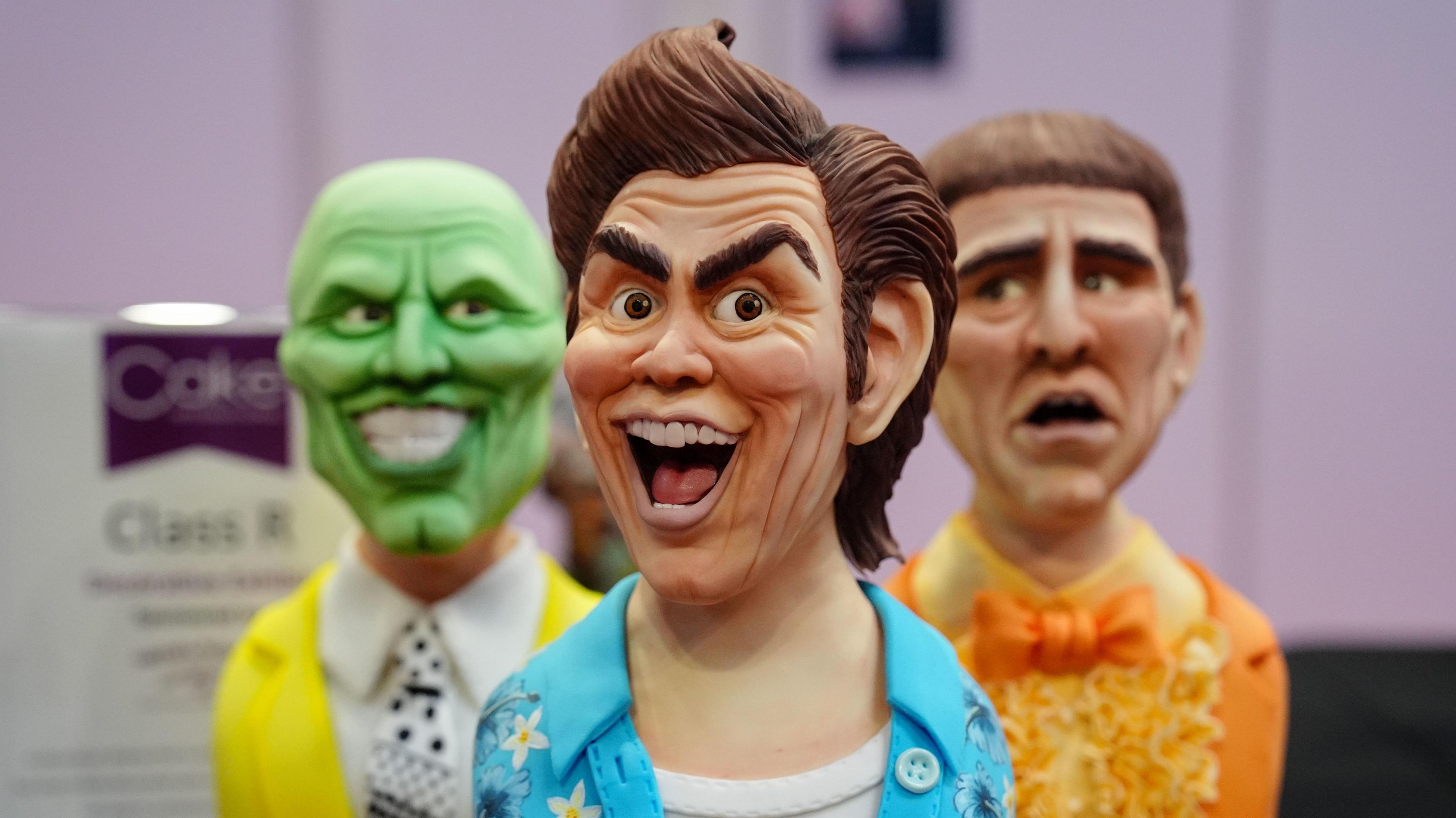 A close-up of three cakes depicting Jim Carrey characters including Ace Ventura and The Mask.