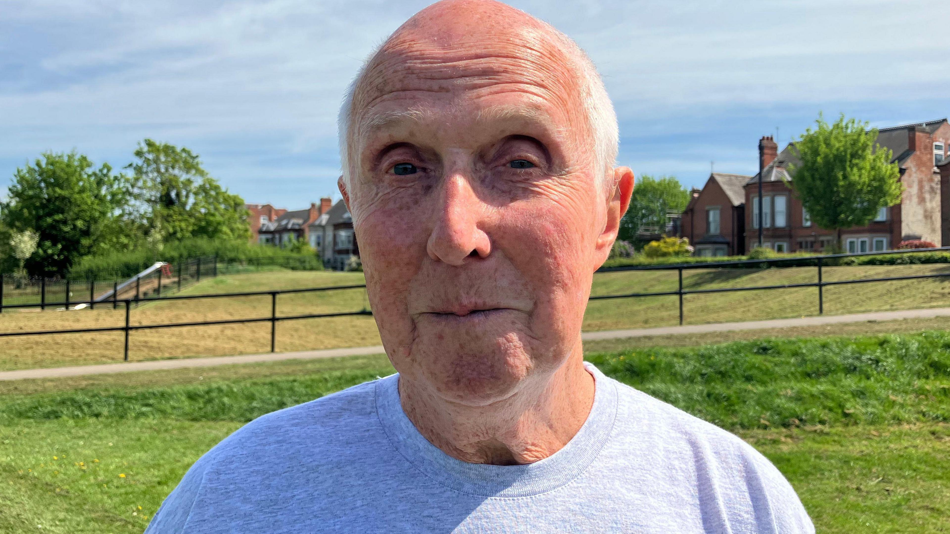 Man with grey hair in t-shirt in field.