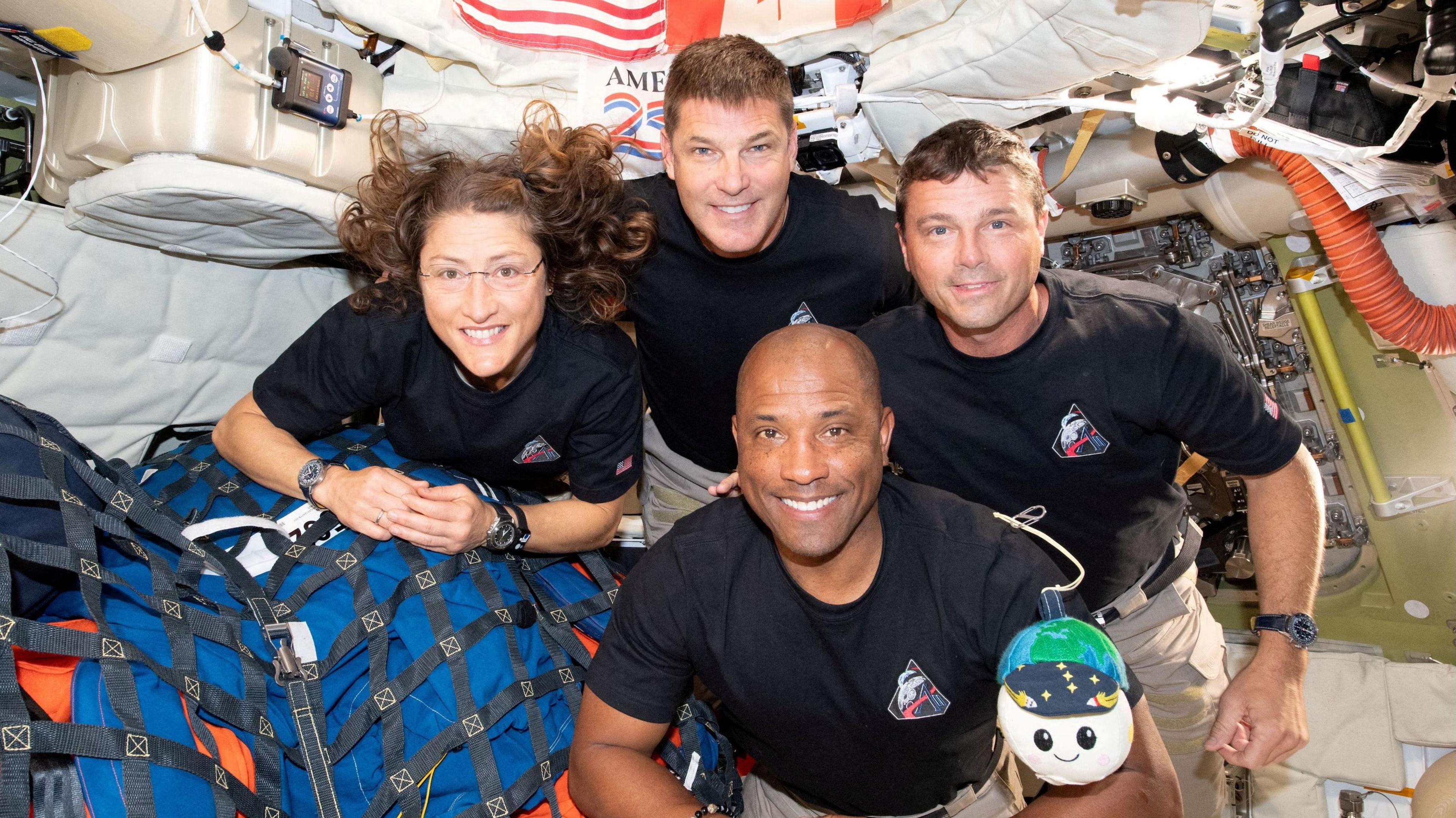 from left going clockwise: Christina Koch, Reid Wiseman, Jeremy Hansen and Victor Glover on board the Orion spacecraft looking into the camera and smiling