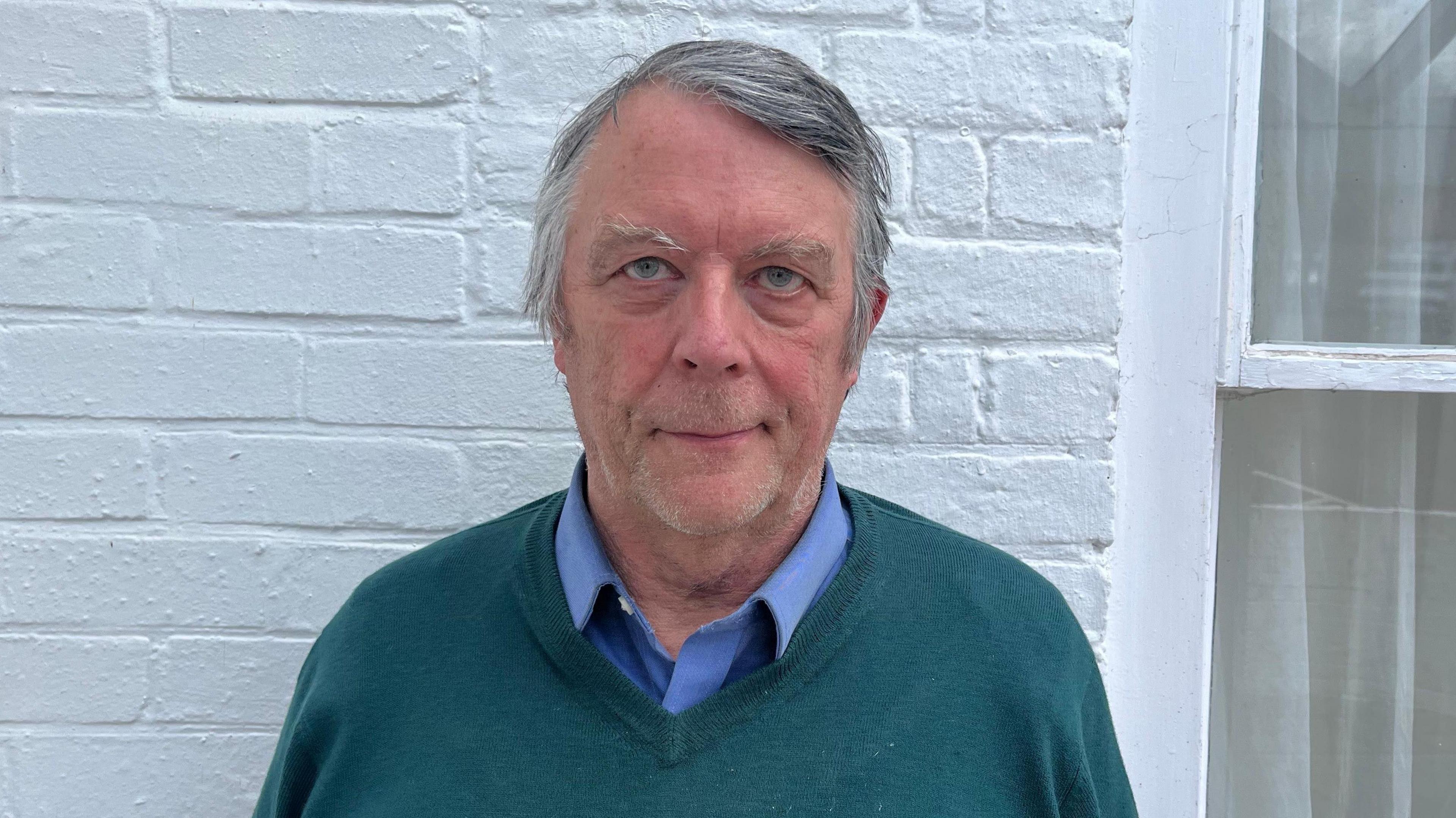 The Marquess of Ailesbury looks at the camera, wearing shirt and jumper.