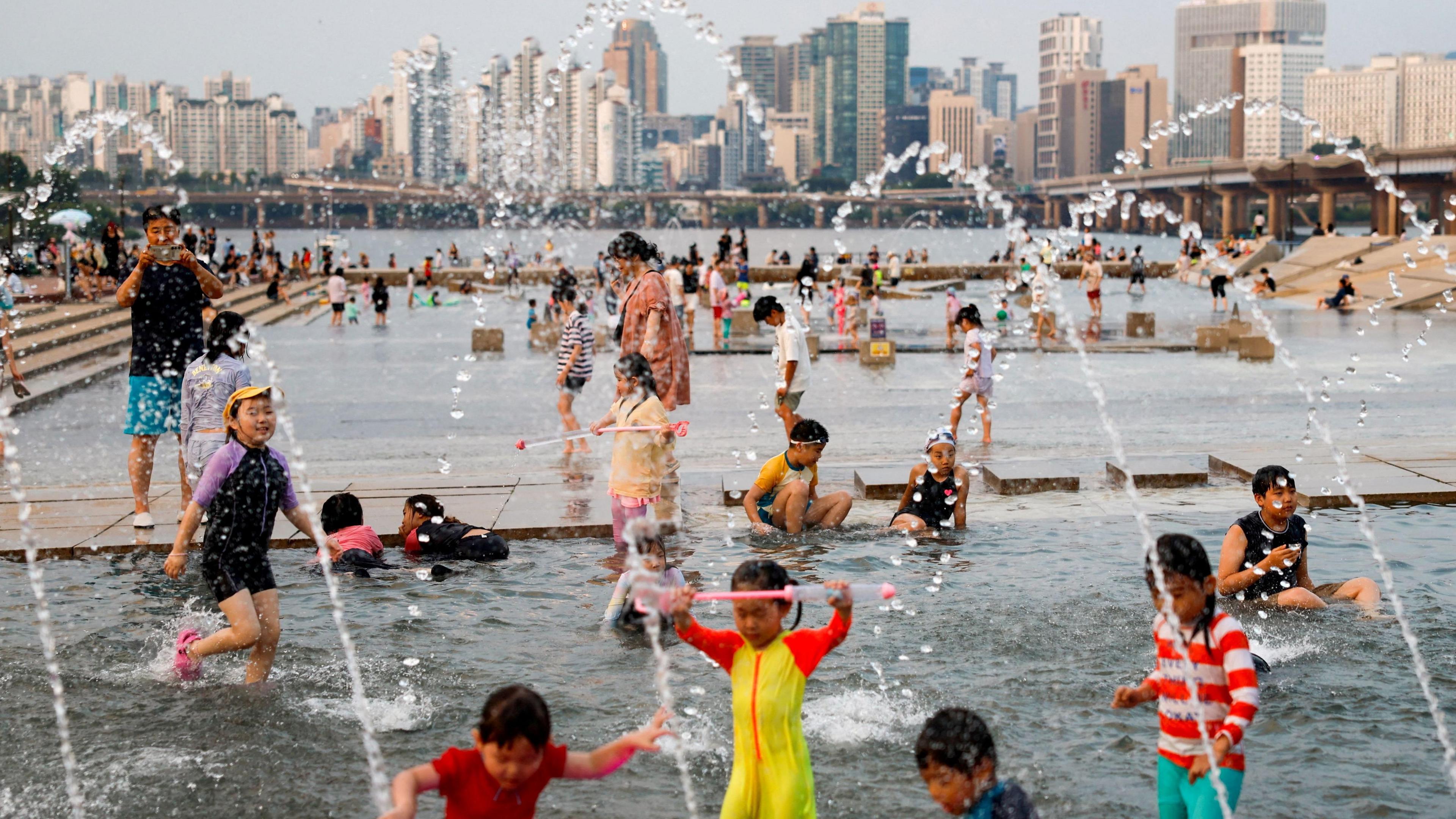 kids and family playing in a water fountain in a South Korean city.