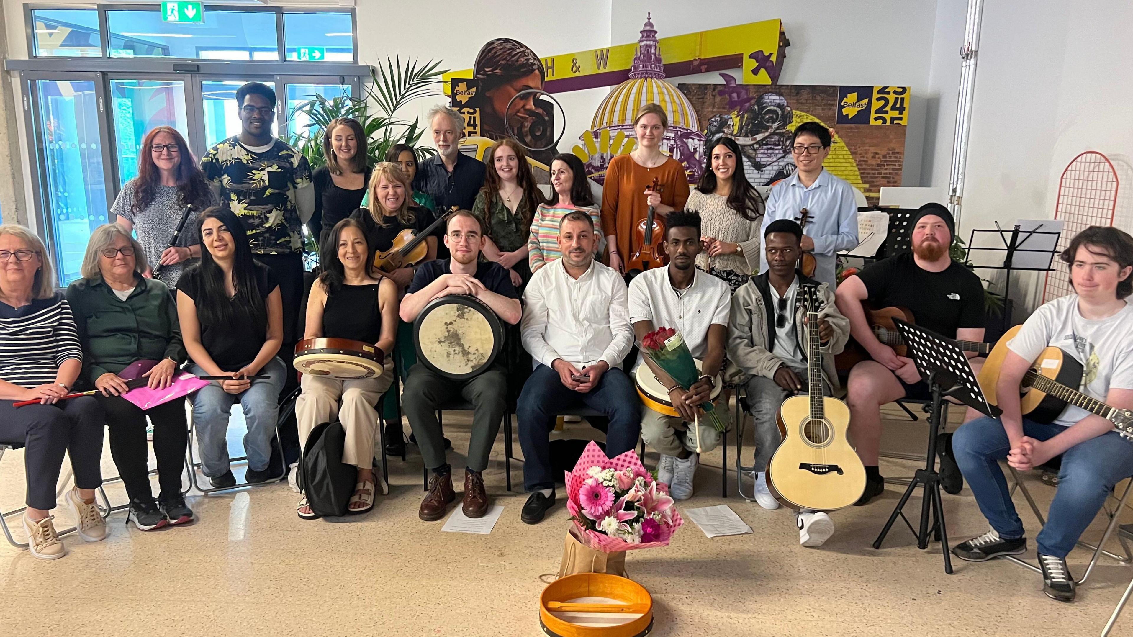 Group of people from different communities sitting together holding instruments such as a guitar. 