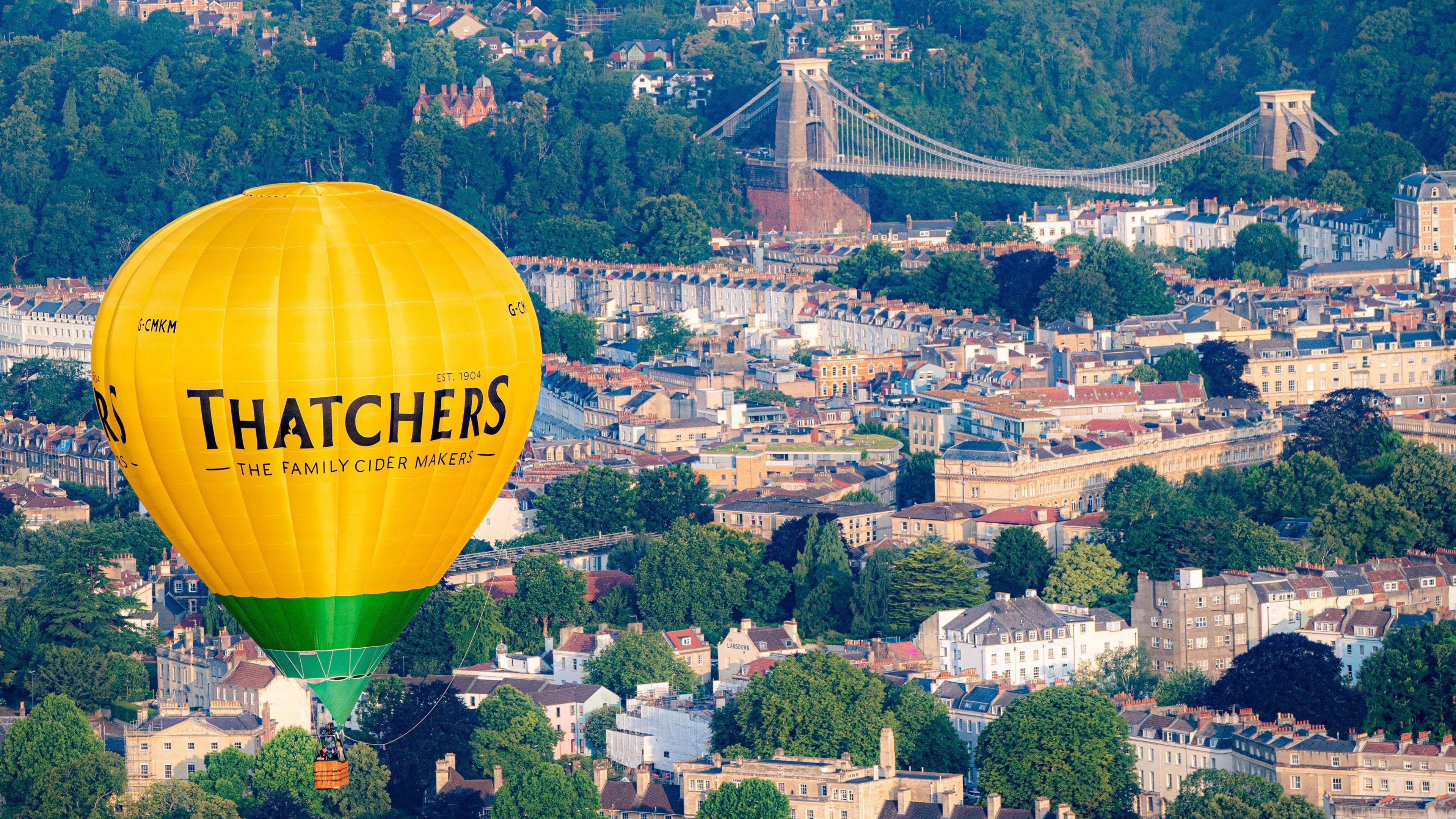 A picture of a hot-air balloon in the foreground and the bridge in the background, taken from the air