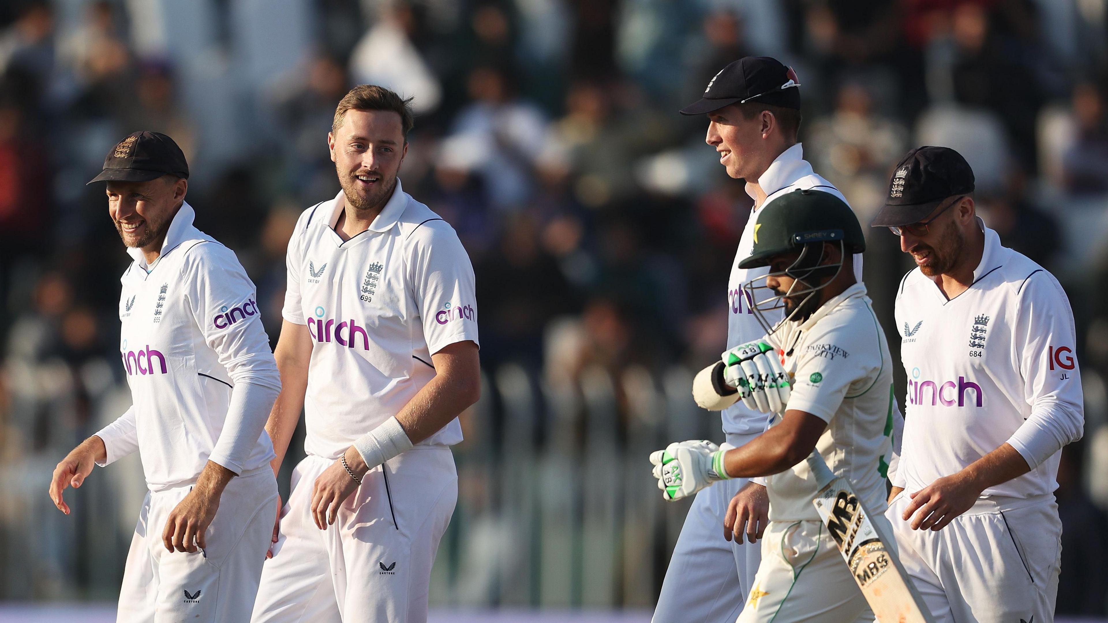 Ollie Robinson (second left) with Joe Root (left), Zak Crawley and Jack Leach (far right) as a Pakistan batter prepares to walk off with the bat tucked under his left arm.