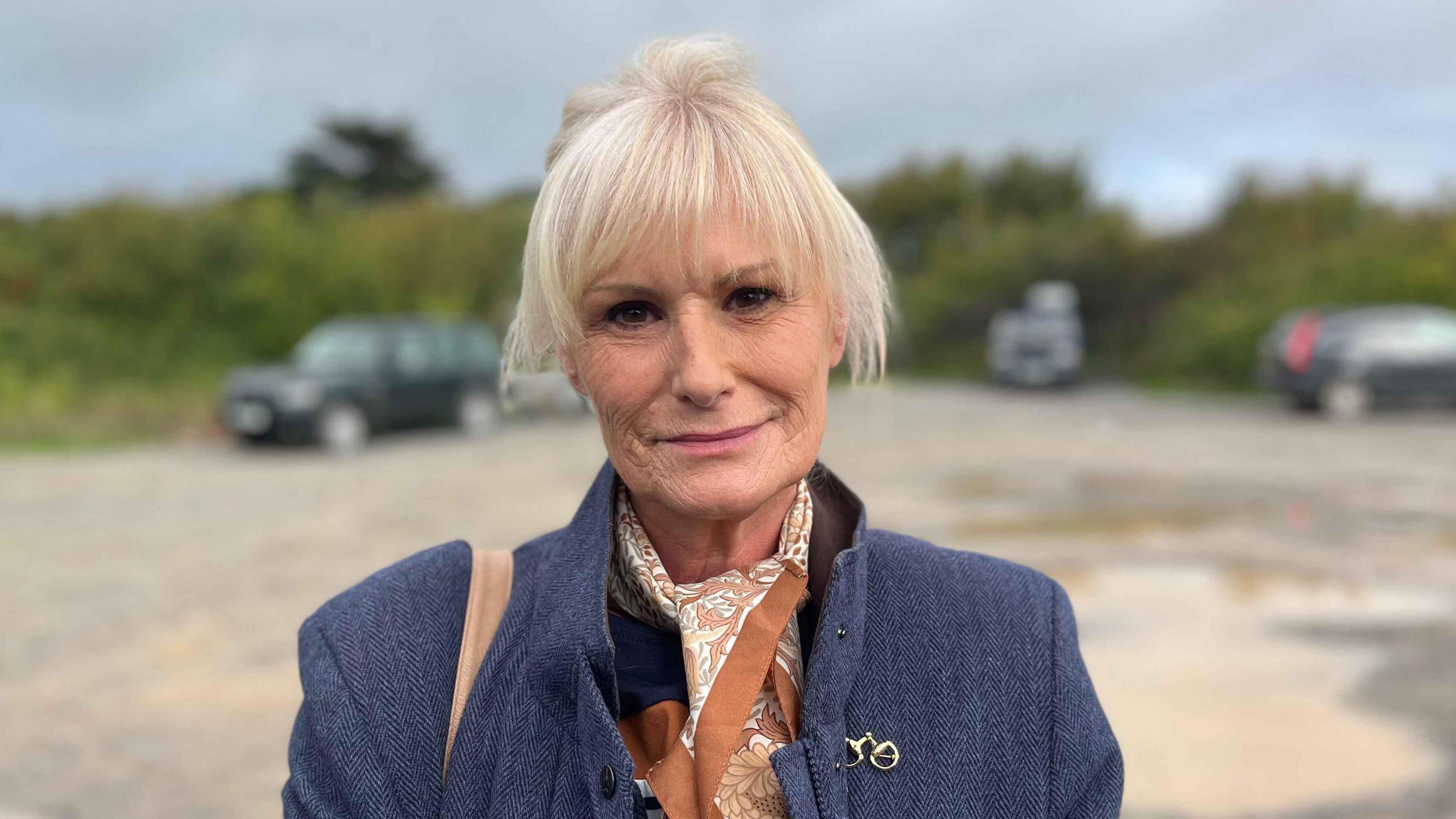 Catherine jones looking at the camera wearing a smart overcoat. She has blonde hair