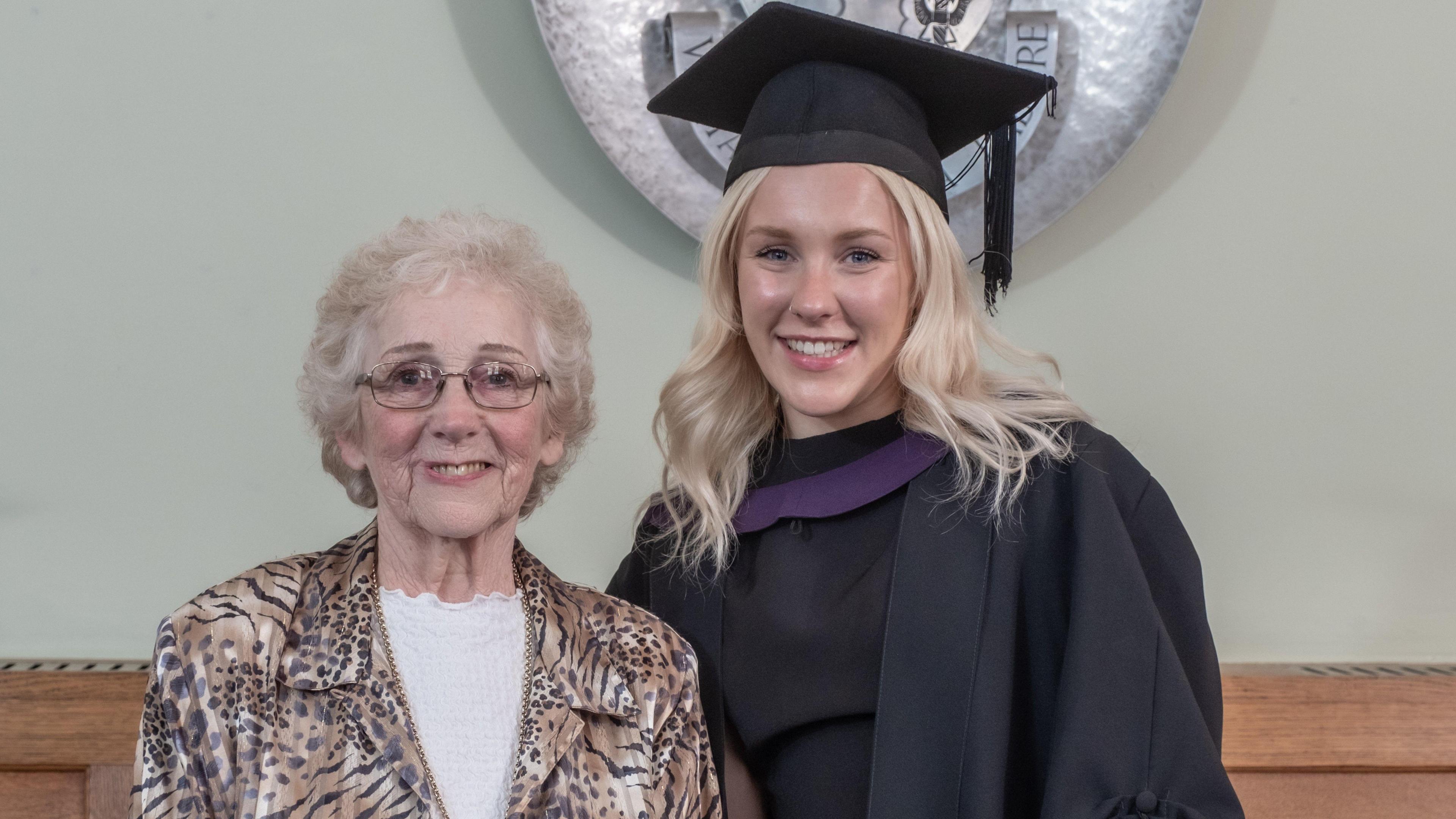 Sandra Freeman, 80, wearing a leopard print jacket standing next to Molly Jackson wearing a graduation gown 