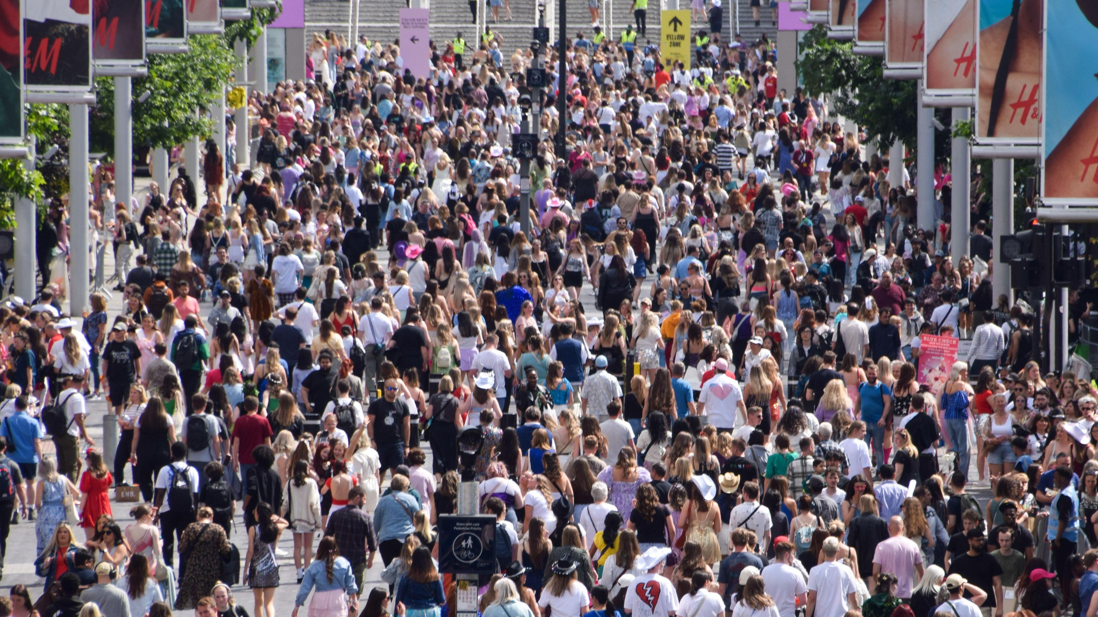 A large crowd of people walk outside Wembley Stadium.