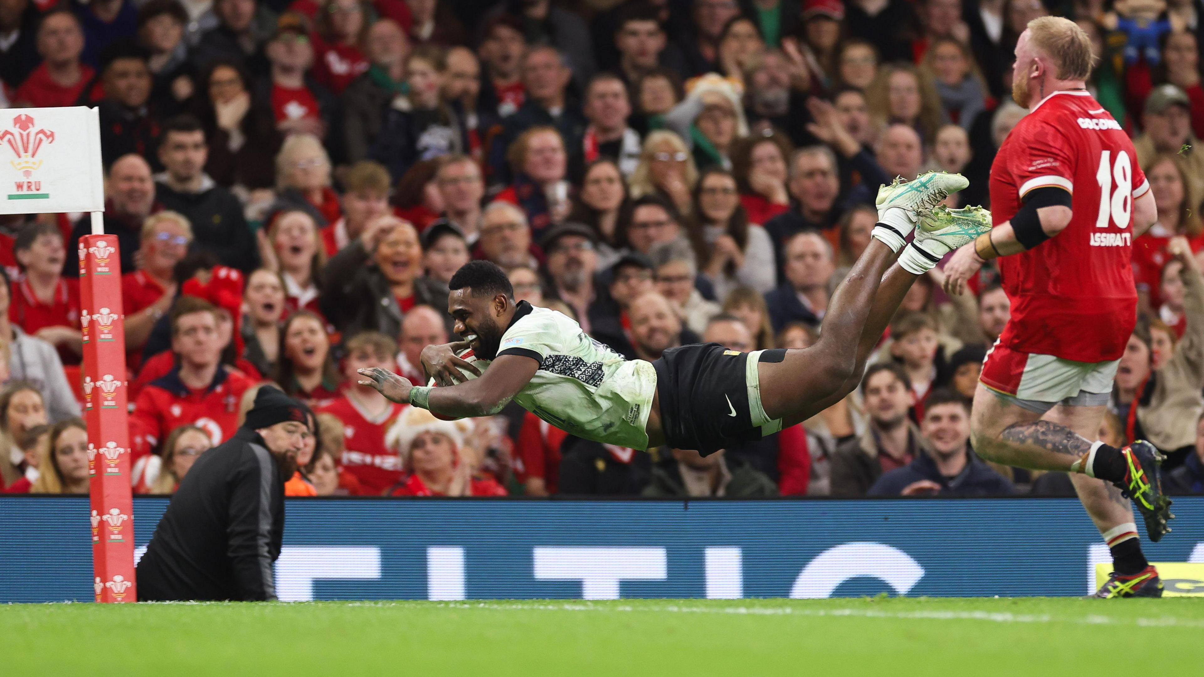 Josua Tuisova in the air as he dives over the line to score for Fiji against Wales in 2024