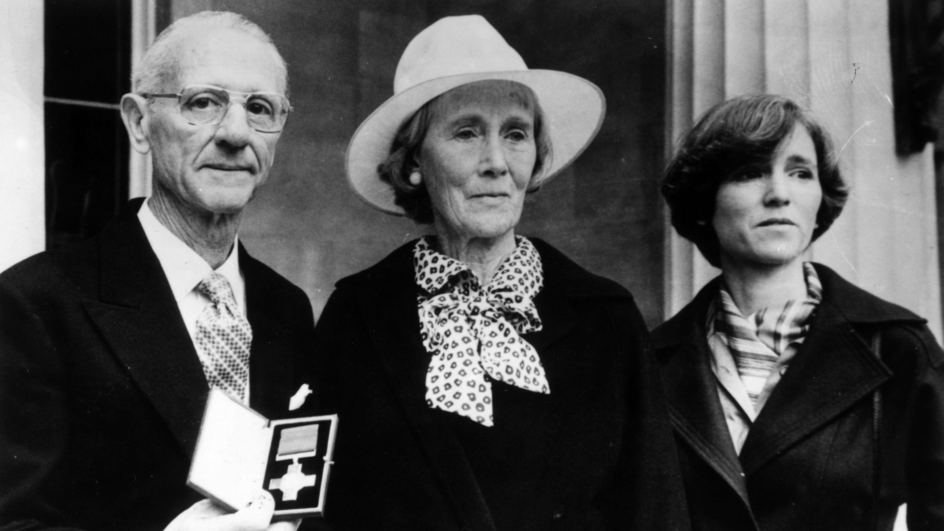 Archive image showing Nairac's family, father Maurice with short grey hair and glasses, mother Barbara with white hat and scarf and sister Rosamonde with short dark hair and dark jacket