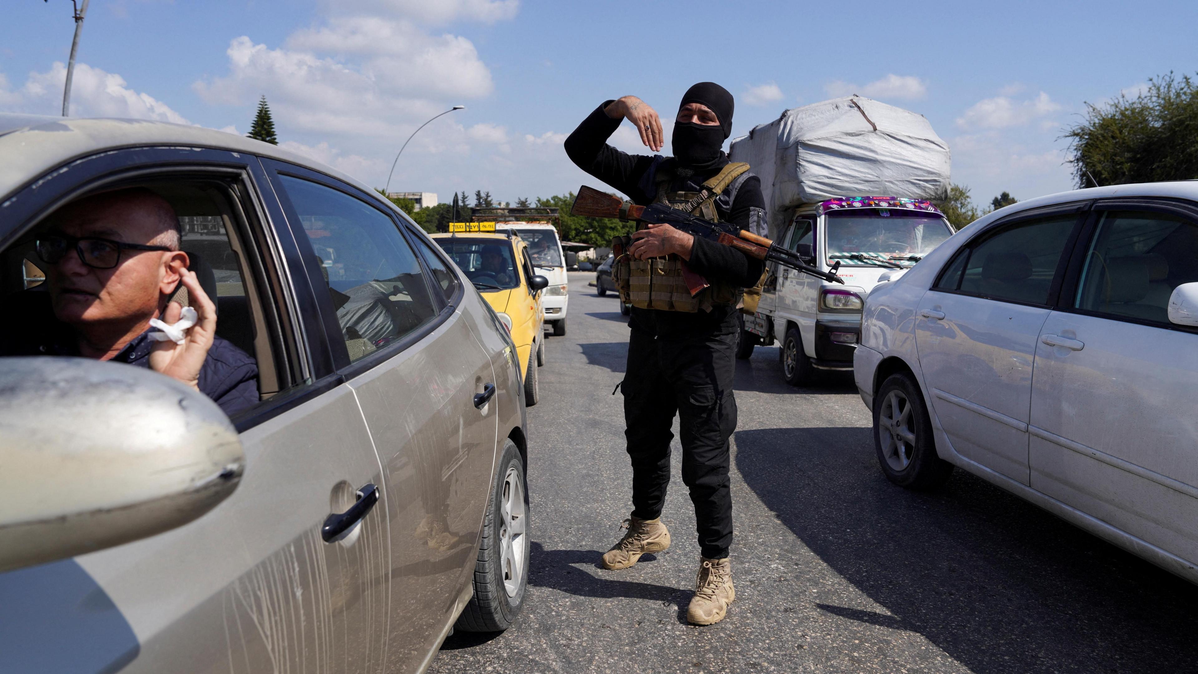 A member of the Syrian security forces gestures towards drivers in Latakia, Syria (10 March 2025)