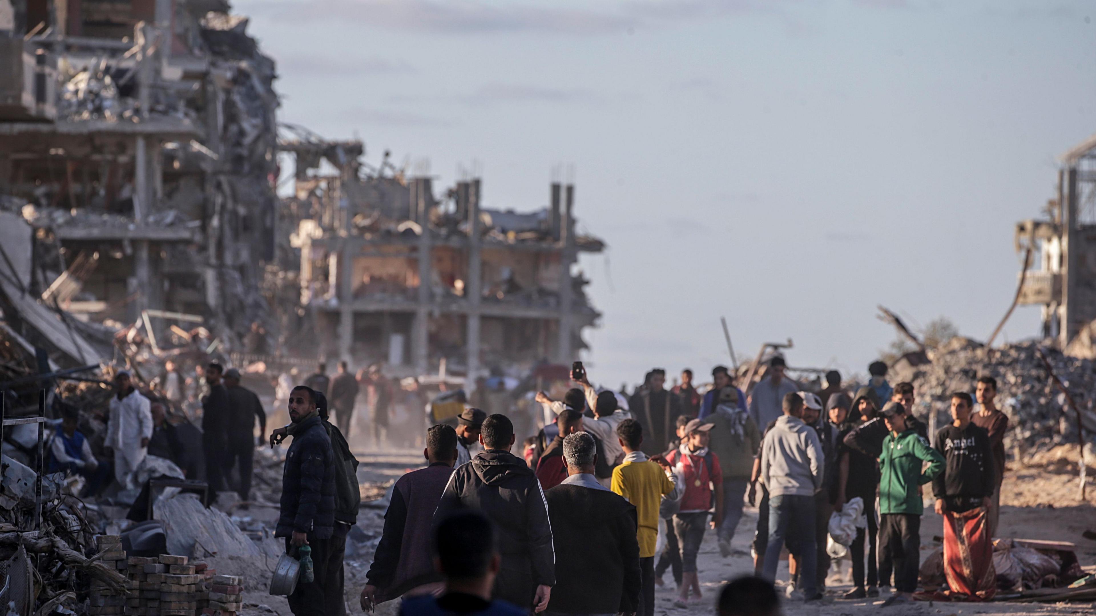 Destruction in Gaza with crowds walking.