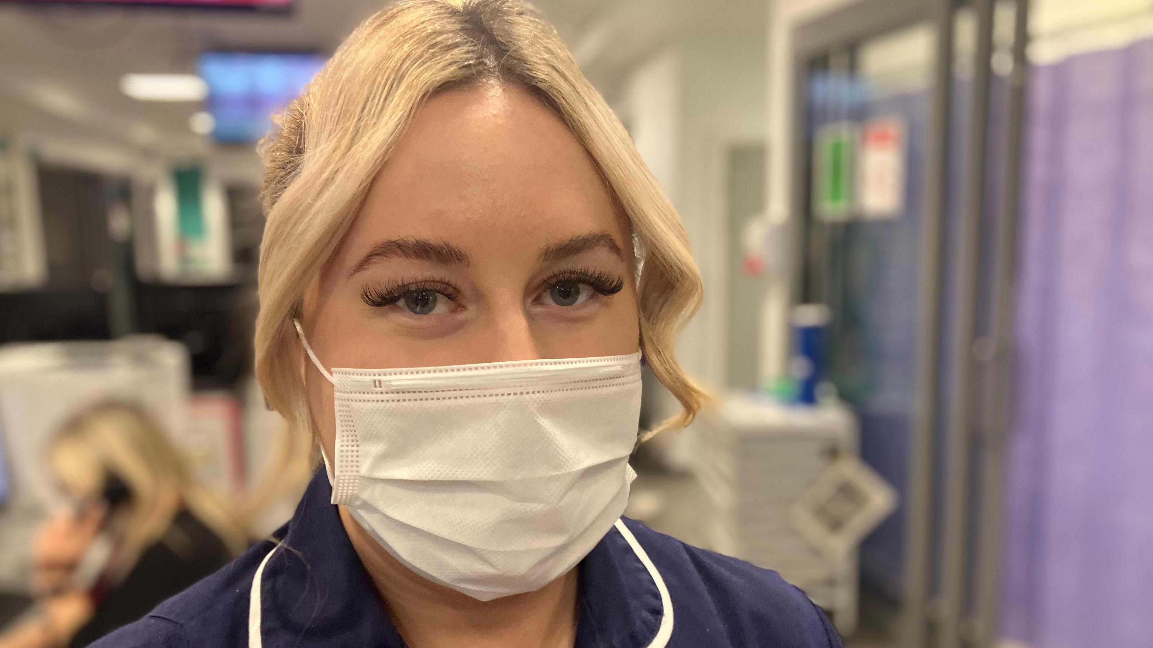 A face-masked nurse in uniform in a hospital 