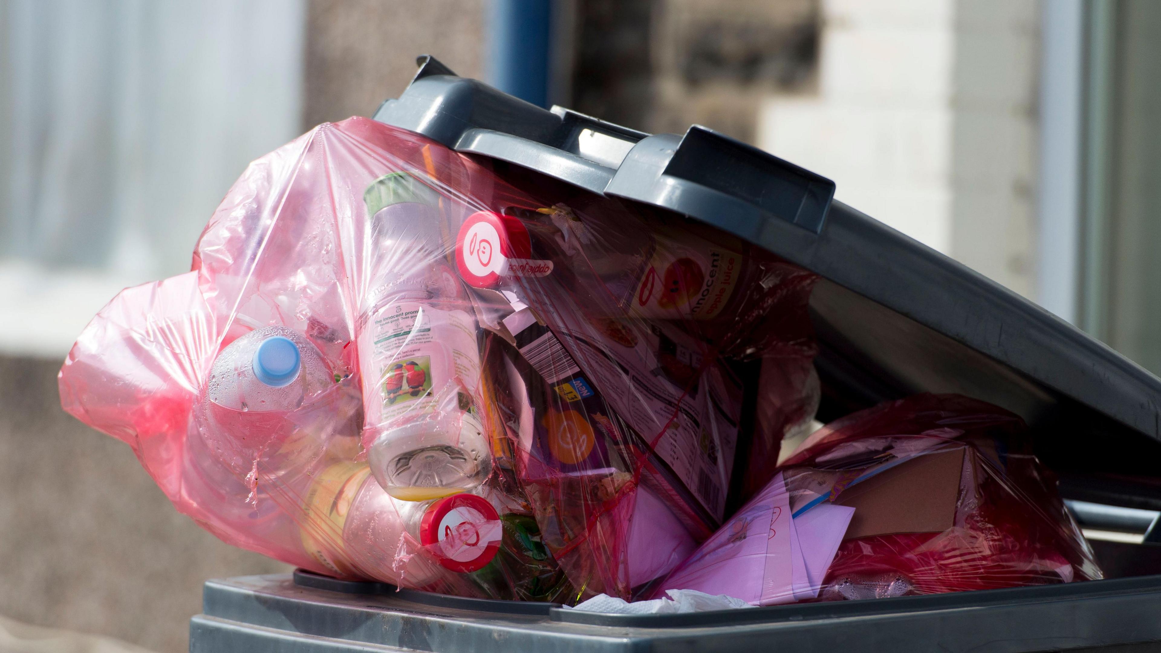 Bag full of recycling in overflowing bin