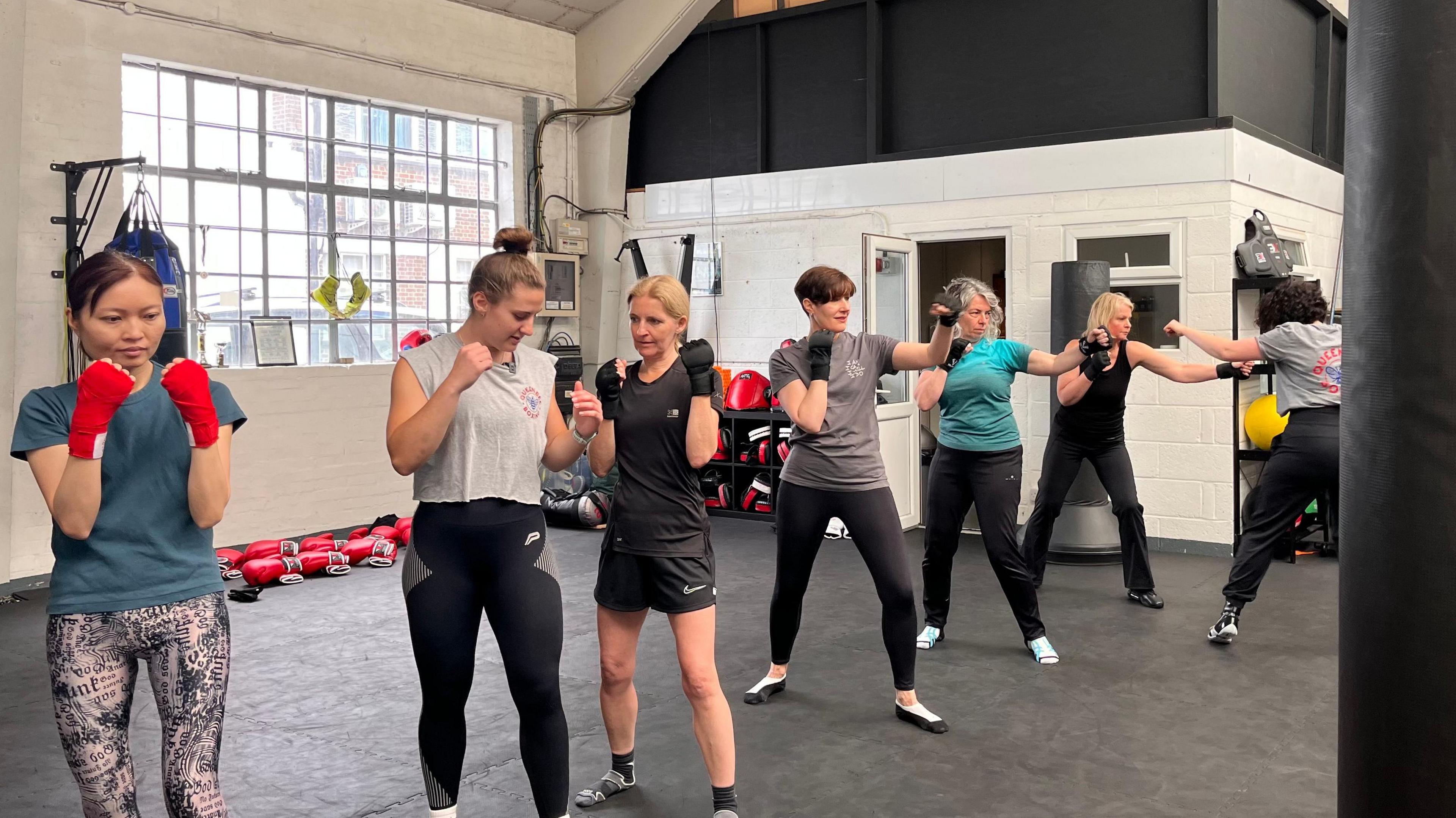 Women learnign how to box in a line inside a club