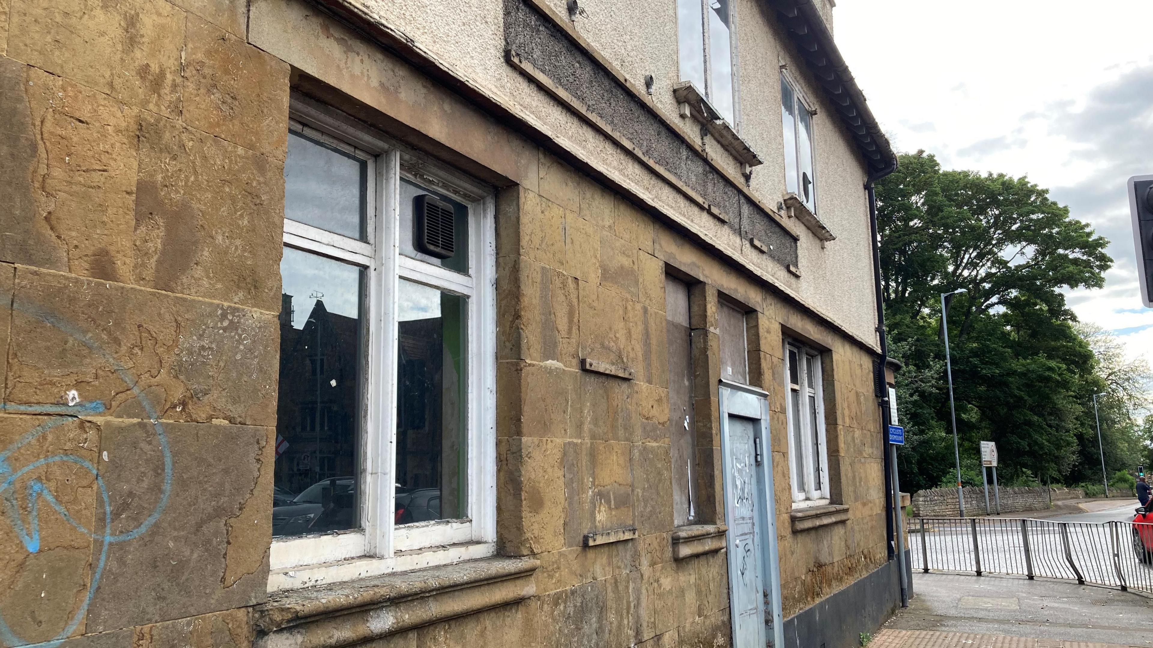 Another facade of the building showing blank sign and graffiti on wall