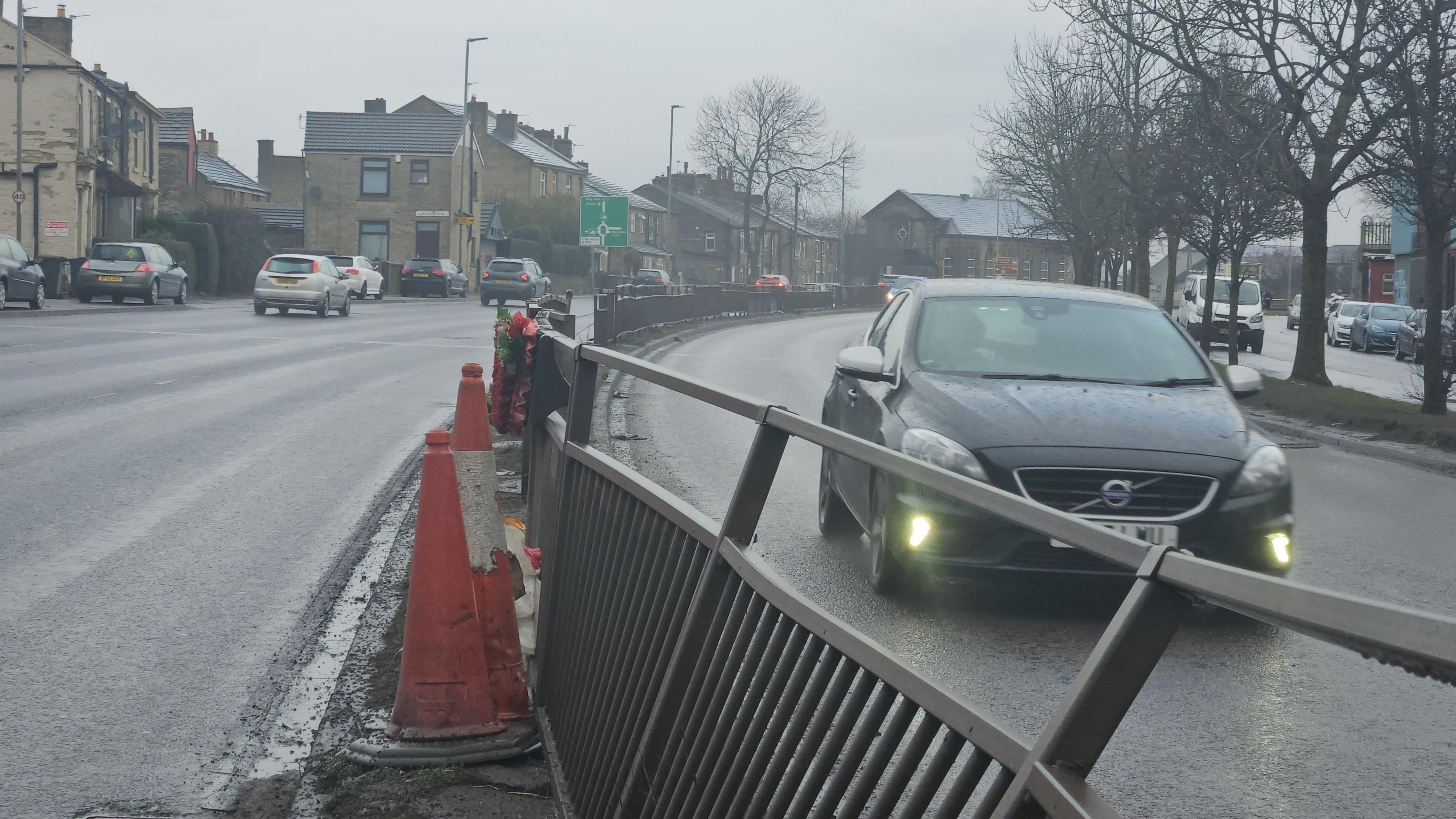 Heavily damaged crash barriers on a dual carriageway, with traffic cones marking them off. Traffic travels past in both directions.