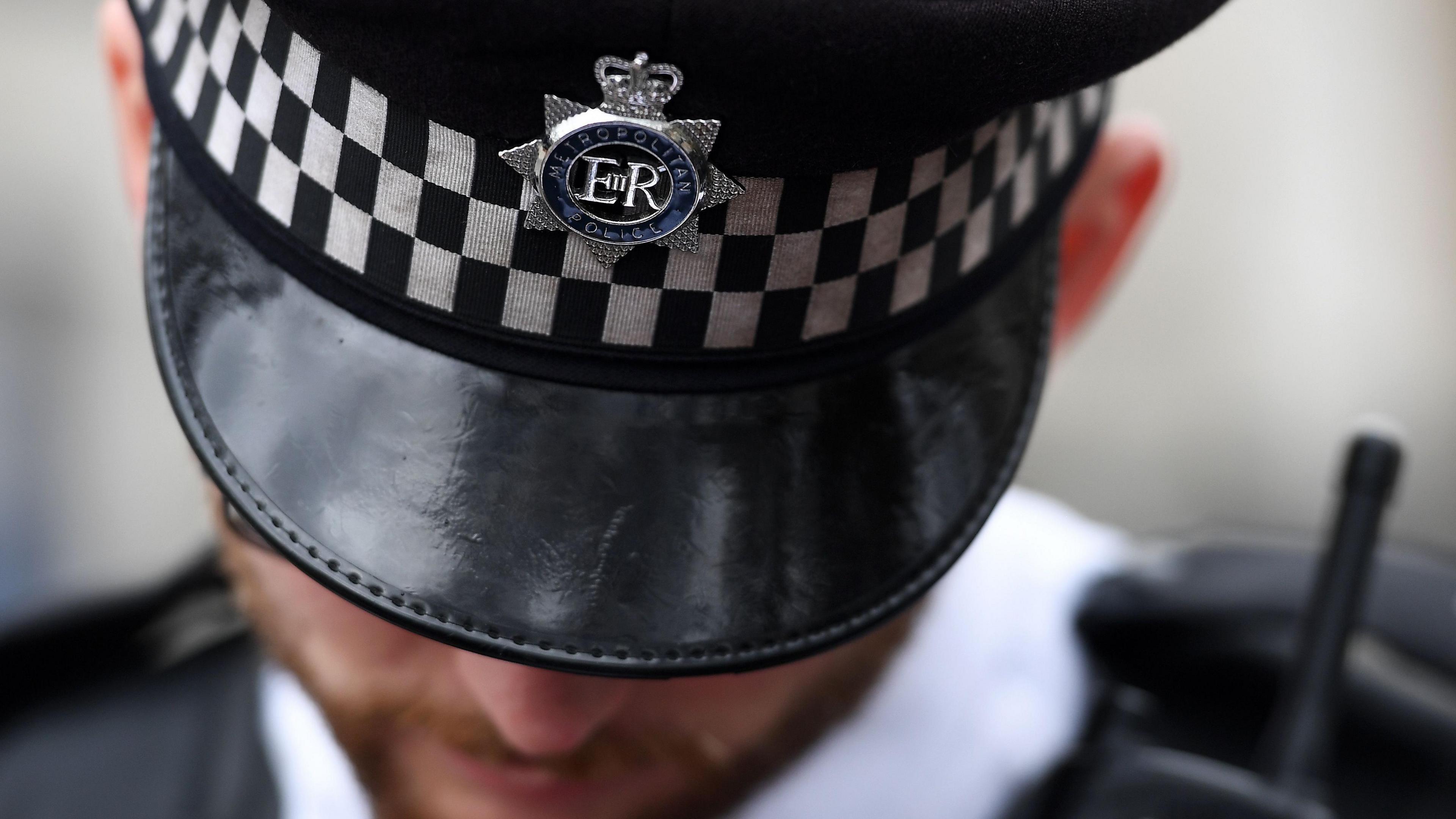 A file image of an anonymous Met Police officer with his face shielded by his hat