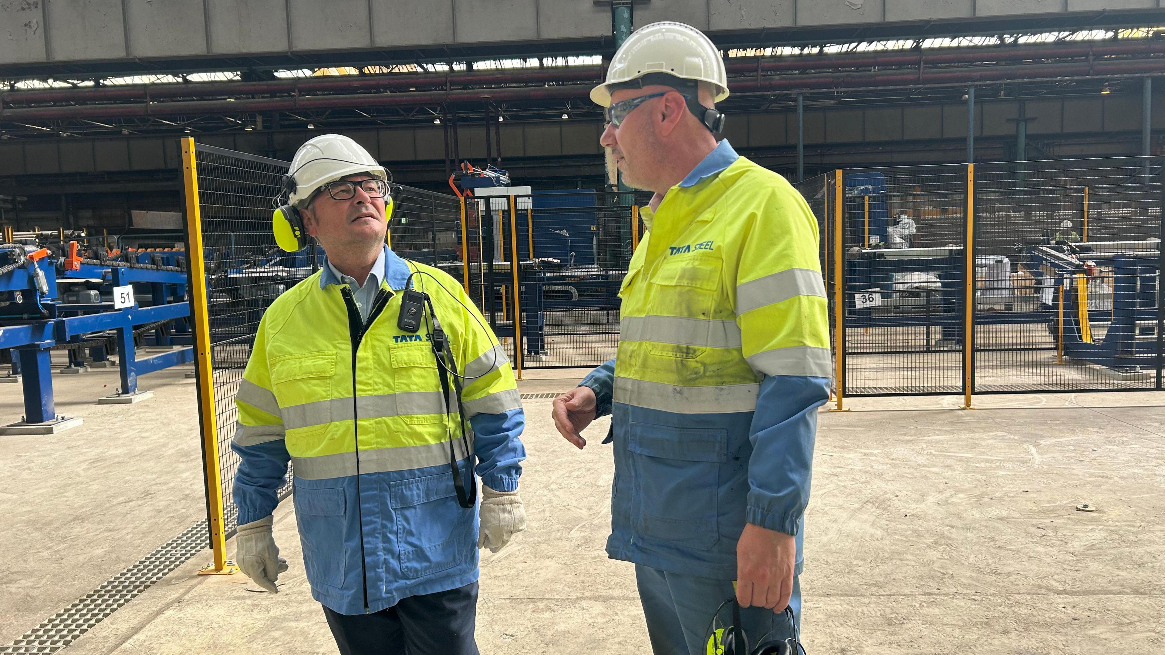 Lee Barron MP, in a high-vis jacket and safety hat, being shown around a steel factory by a representative of Tata Steel, who is also wearing safety gear