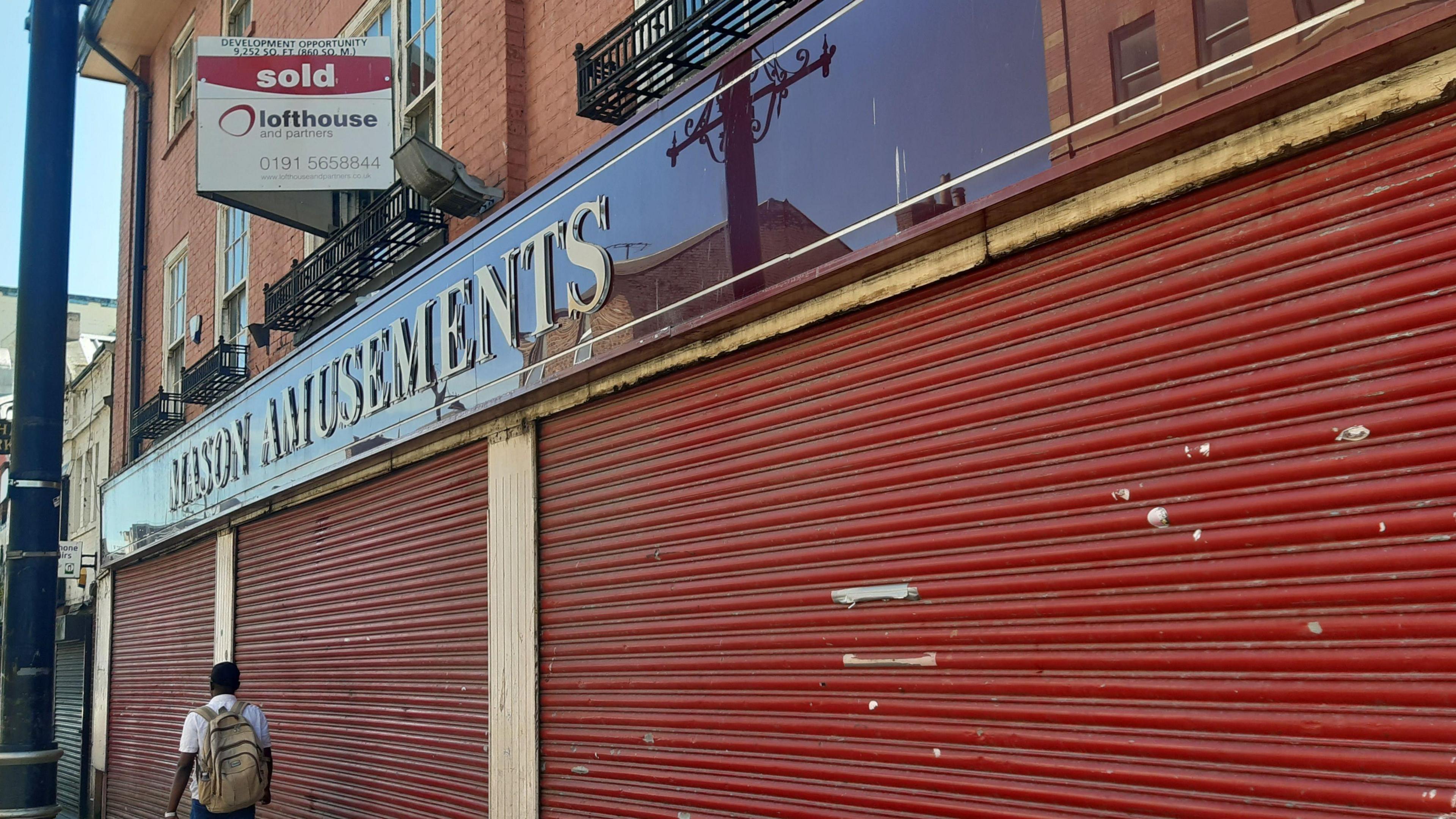 A close-up of the sign above the former Mason Amusements building in Holmeside, Sunderland, with a 'sold' sign and closed shutters